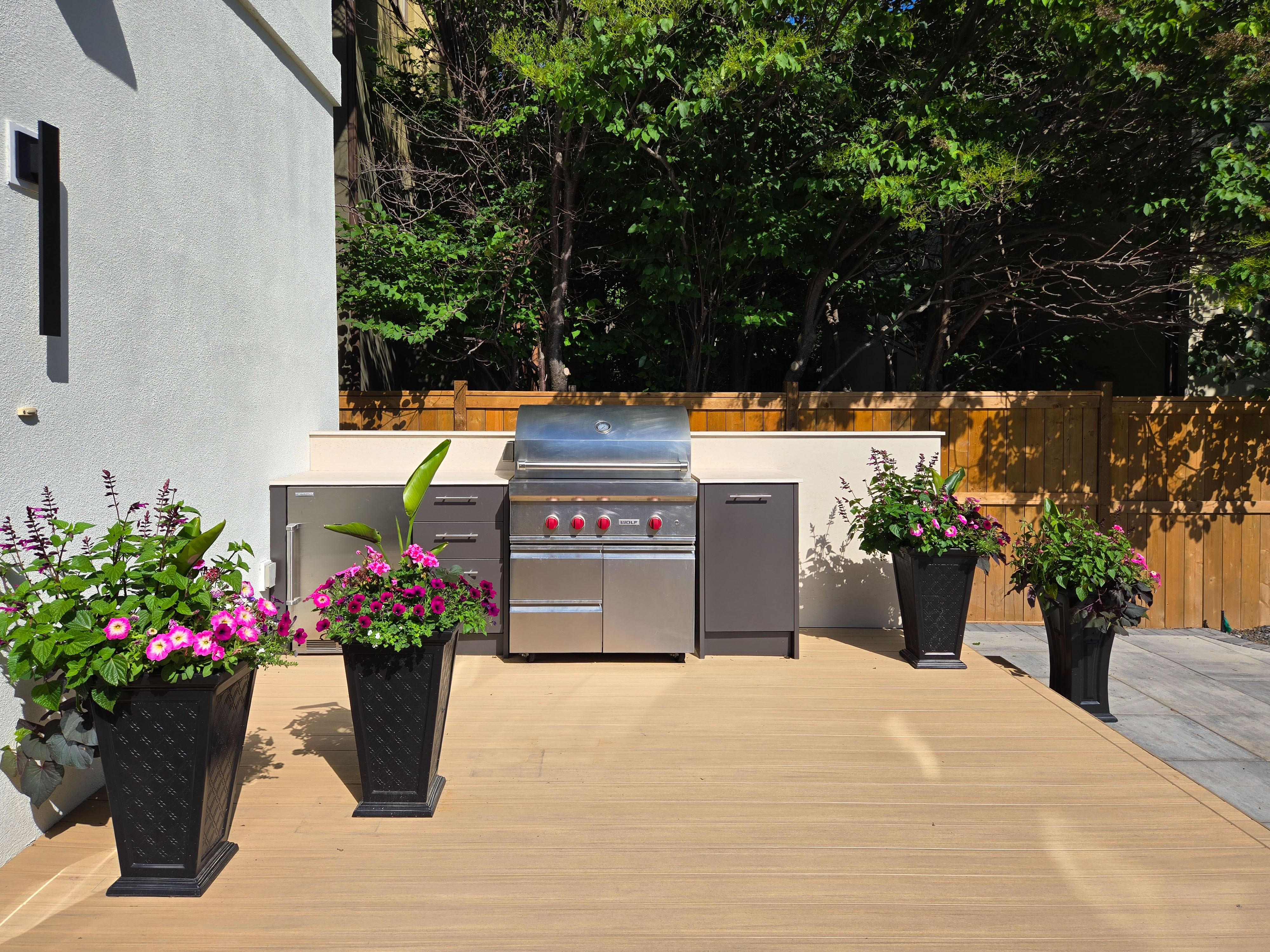 Image of Outdoor kitchen design with grill, cabinetry, and decorative planters on a wooden deck by KHD Homes.