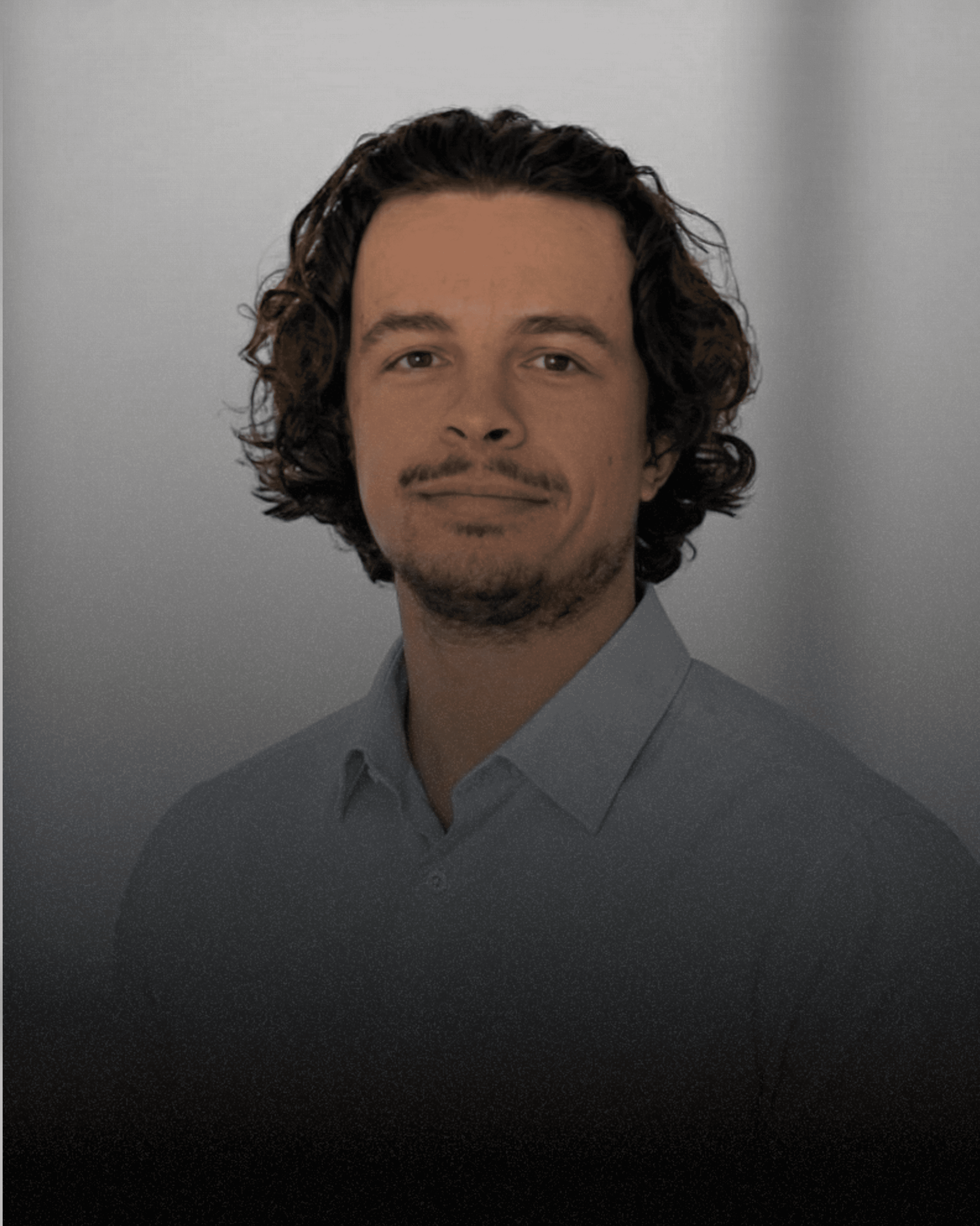 A portrait of a young woman with long, wavy brown hair wearing a mauve knitted sweater and a ring, posing against a light-colored ribbed wall.