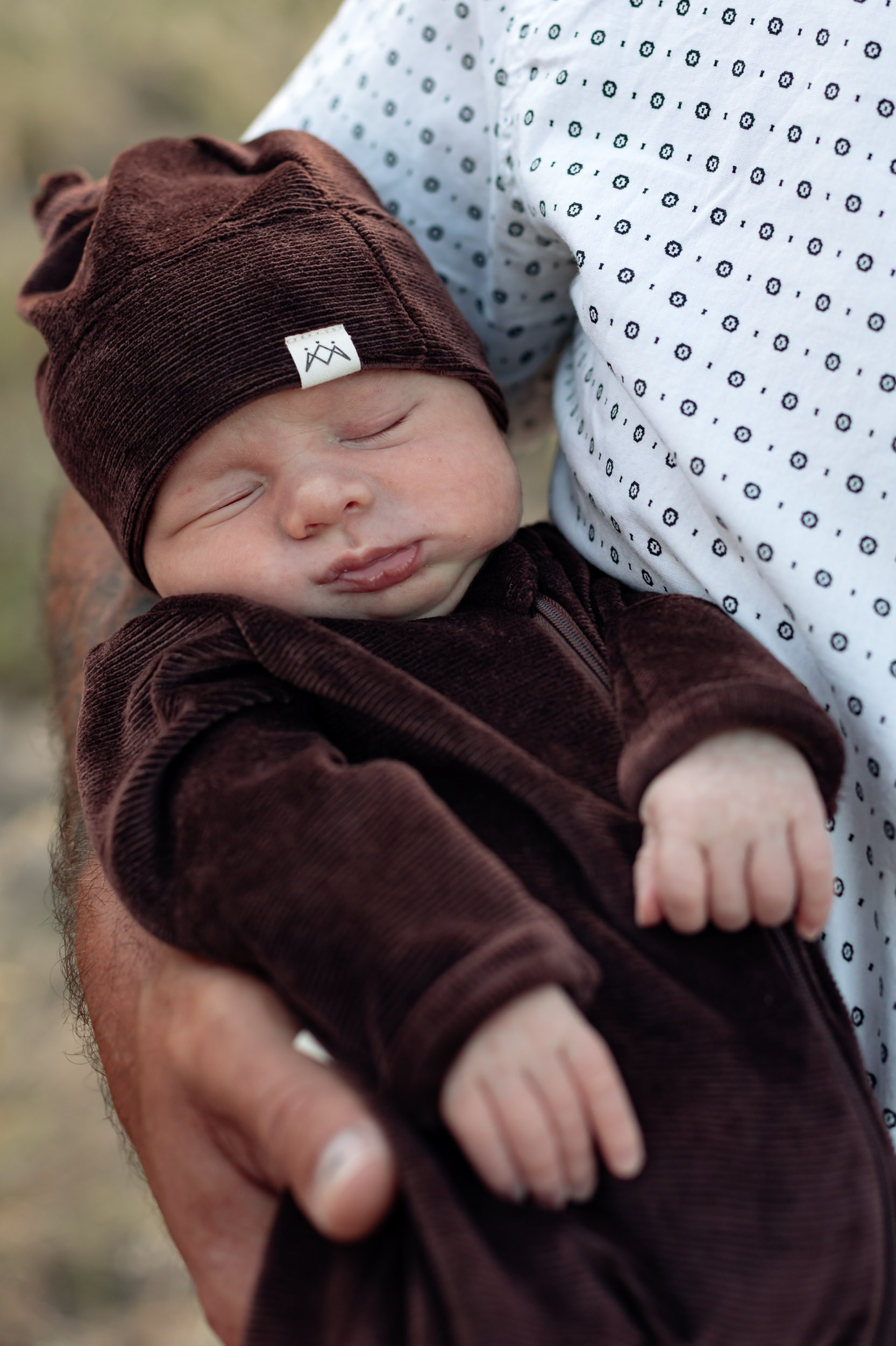 Sleeping newborn baby held in fathers arm