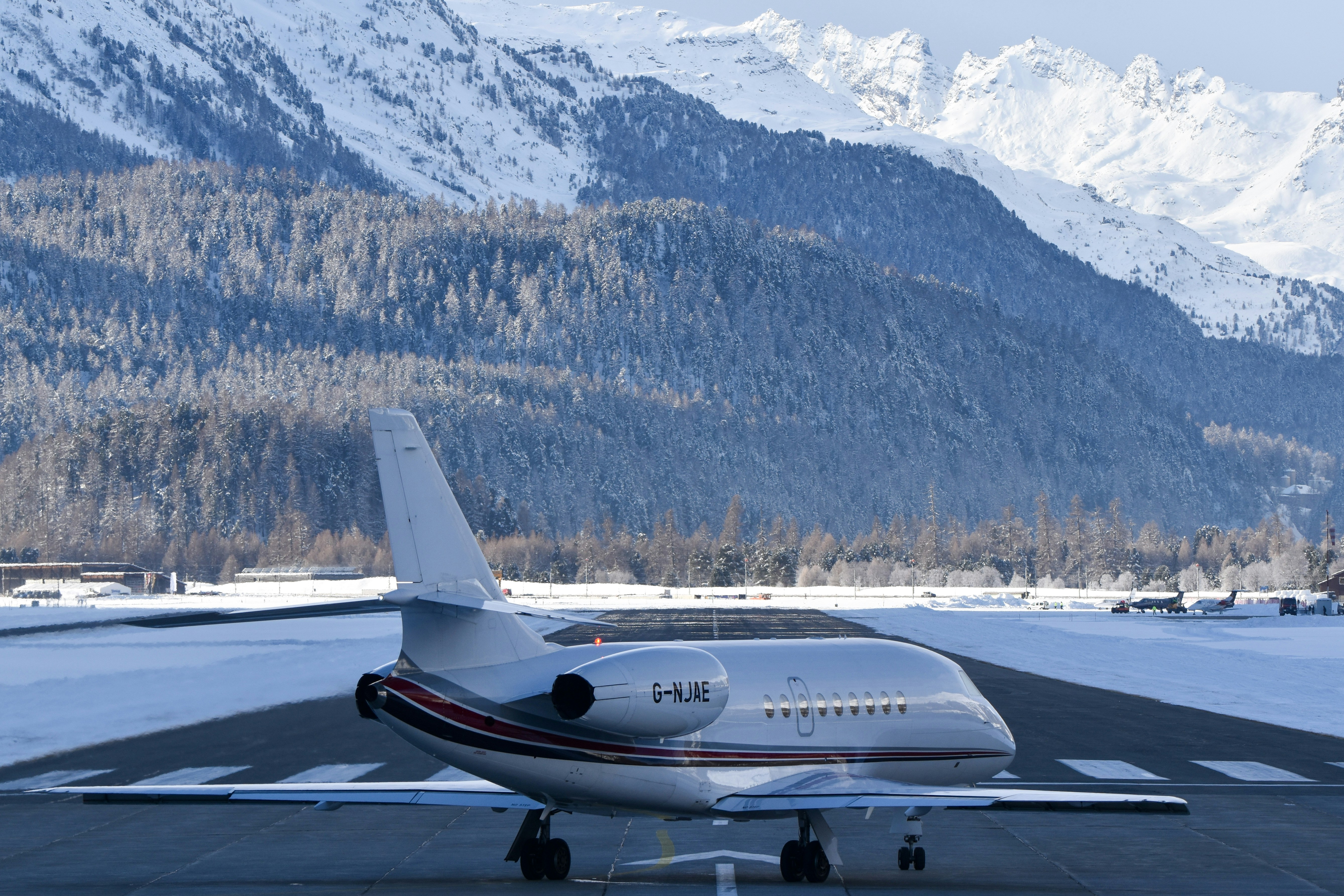 Private jet on a snowy runway with mountains behind