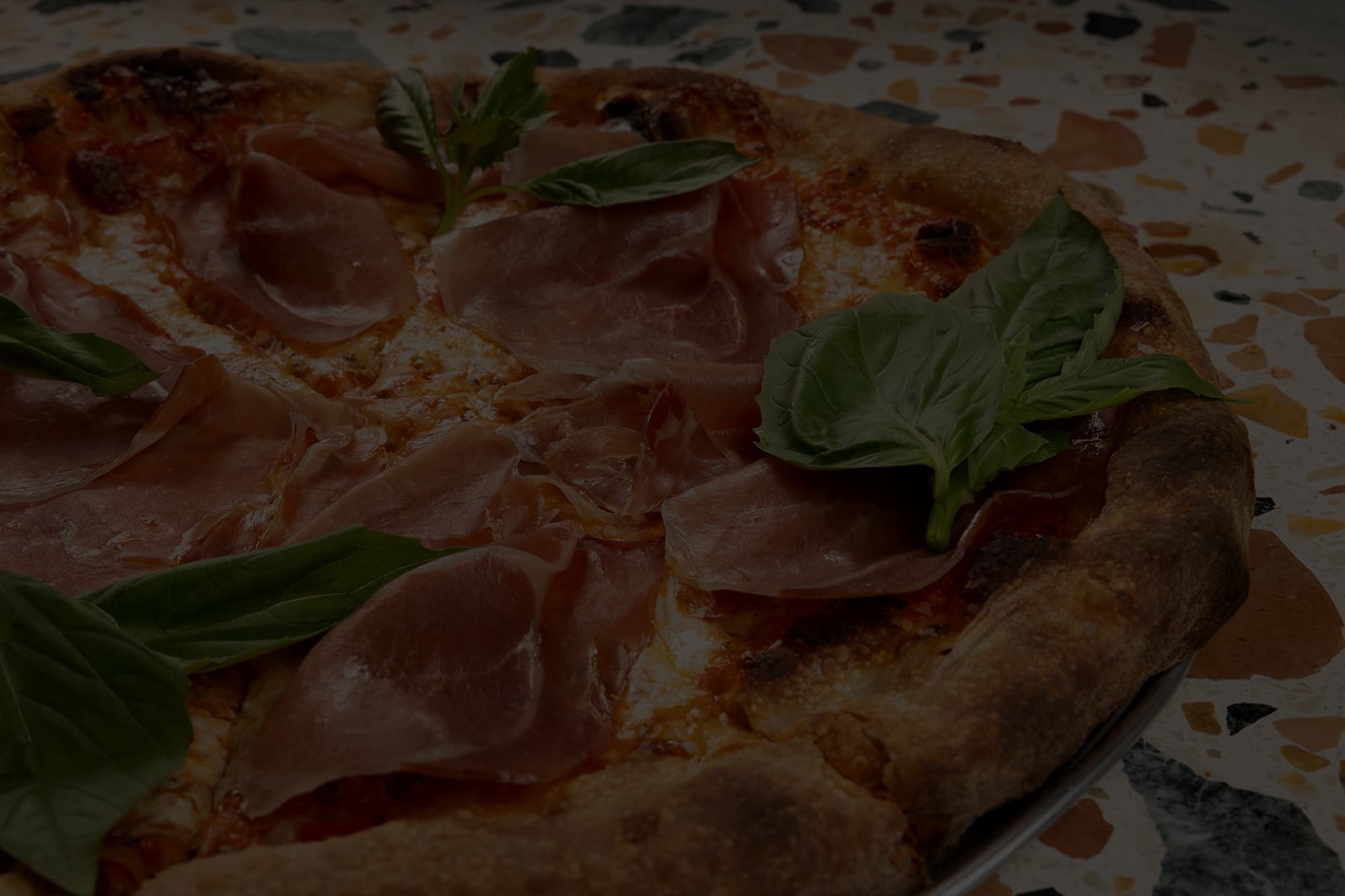 Close-up of a pepperoni pizza with melted cheese, basil leaves, and charred crust edges