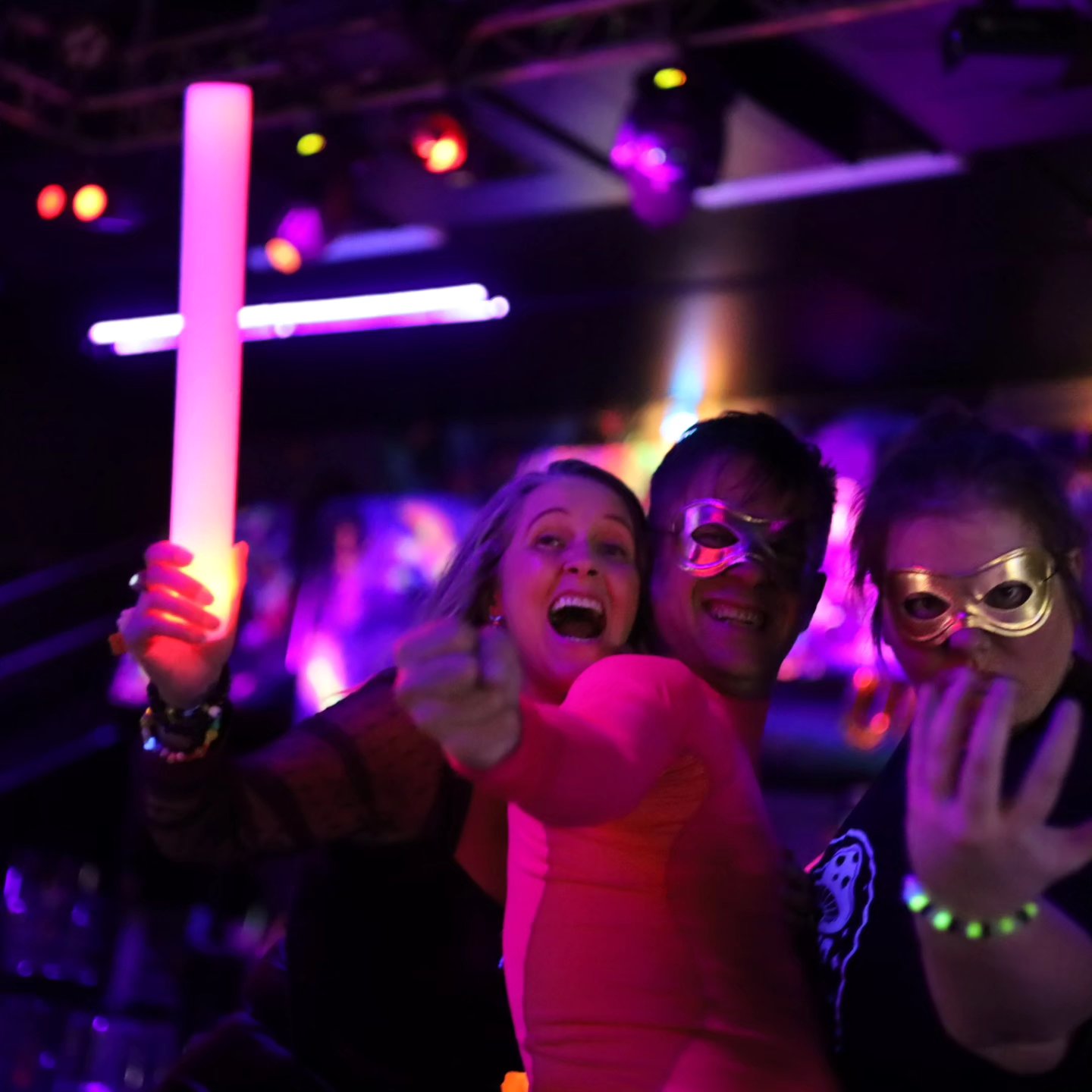 Friends in masks at a neon-lit event