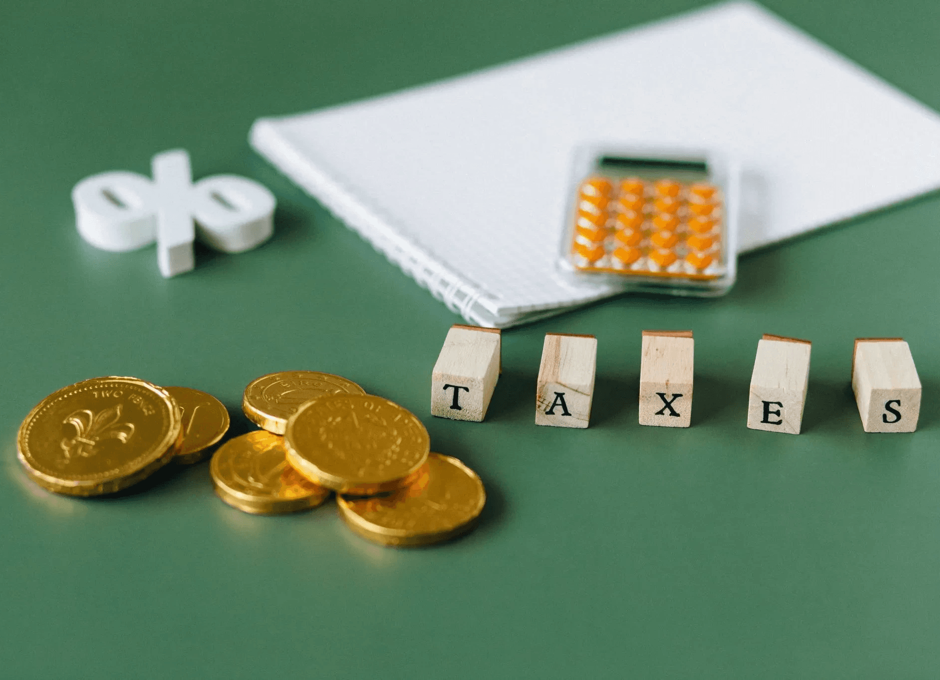 Munten, een rekenmachine en letterblokjes met het woord taxes