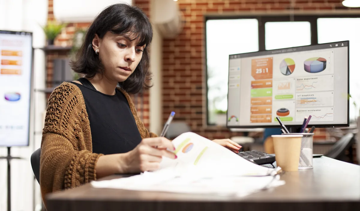 Manager reviewing printed sales charts at her desk