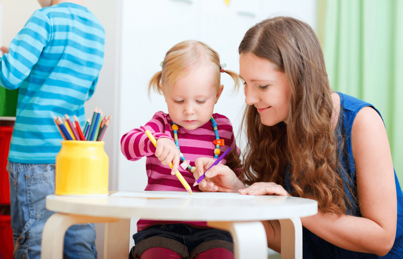 woman watching young girl using pencil