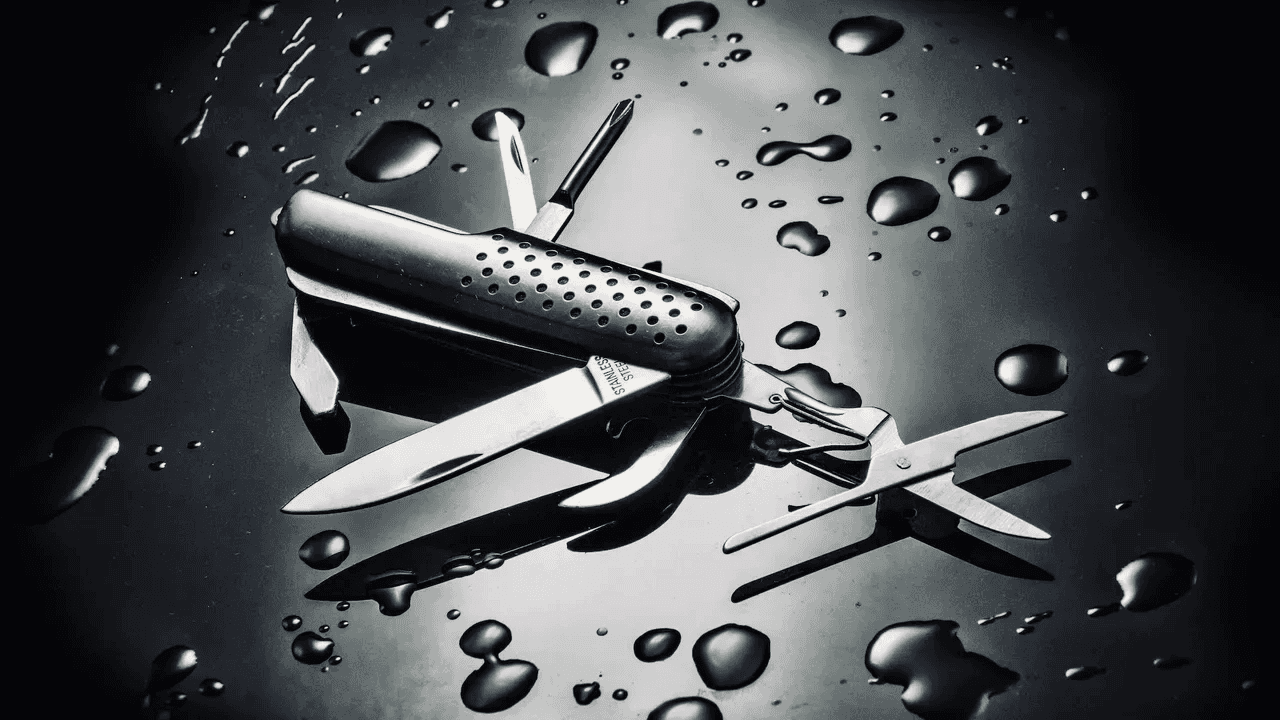 High angle shot of metal multi-purpose knife with water droplets isolated on black surface