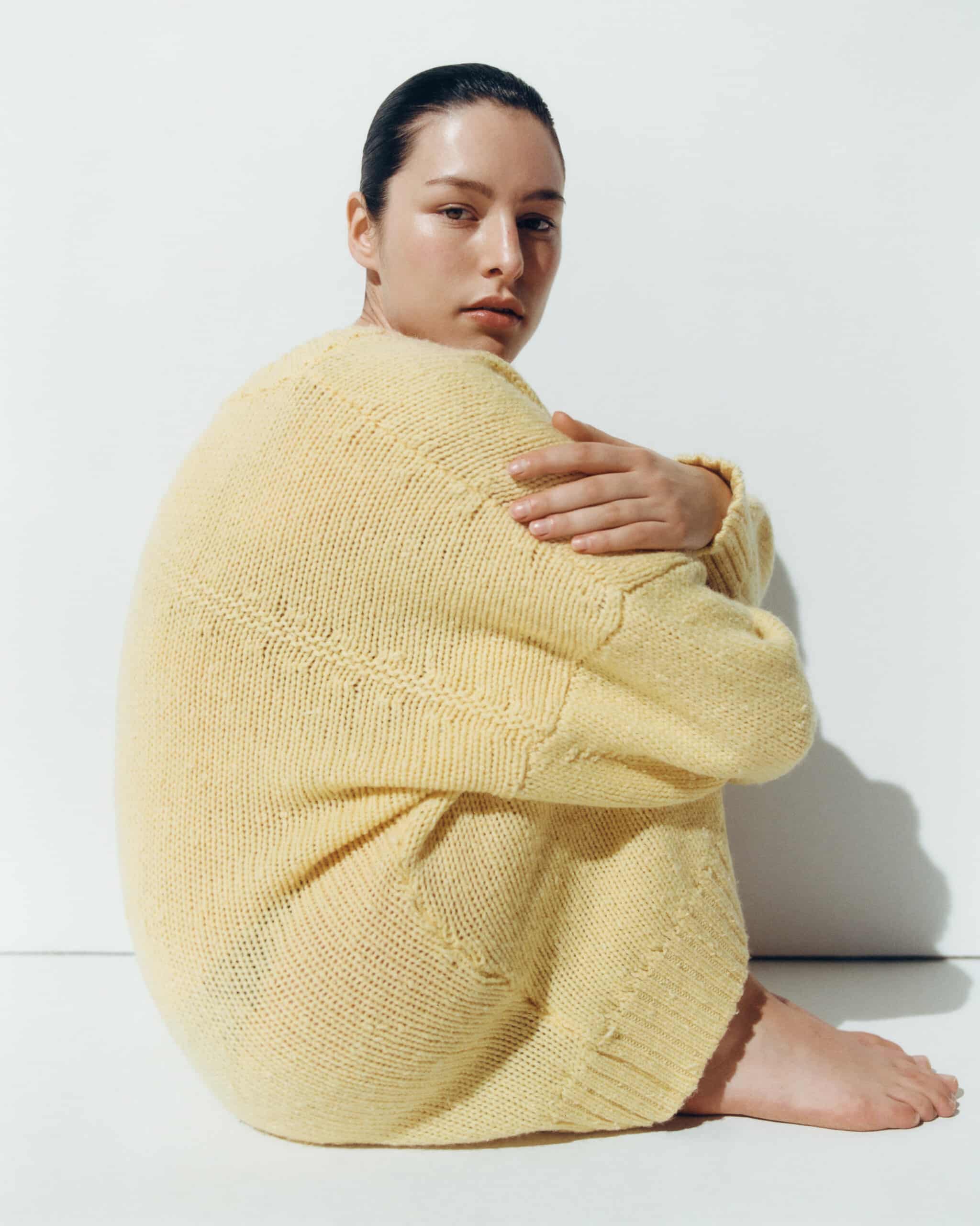 Une femme est assise dans une robe en maille jaune