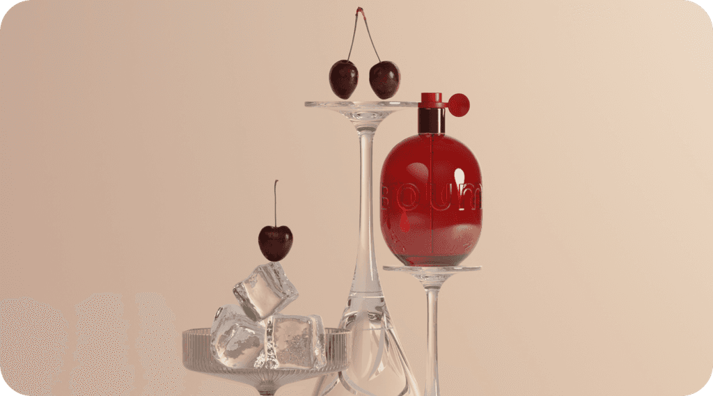 Red perfume bottle next to glasses with cherries on beige background
