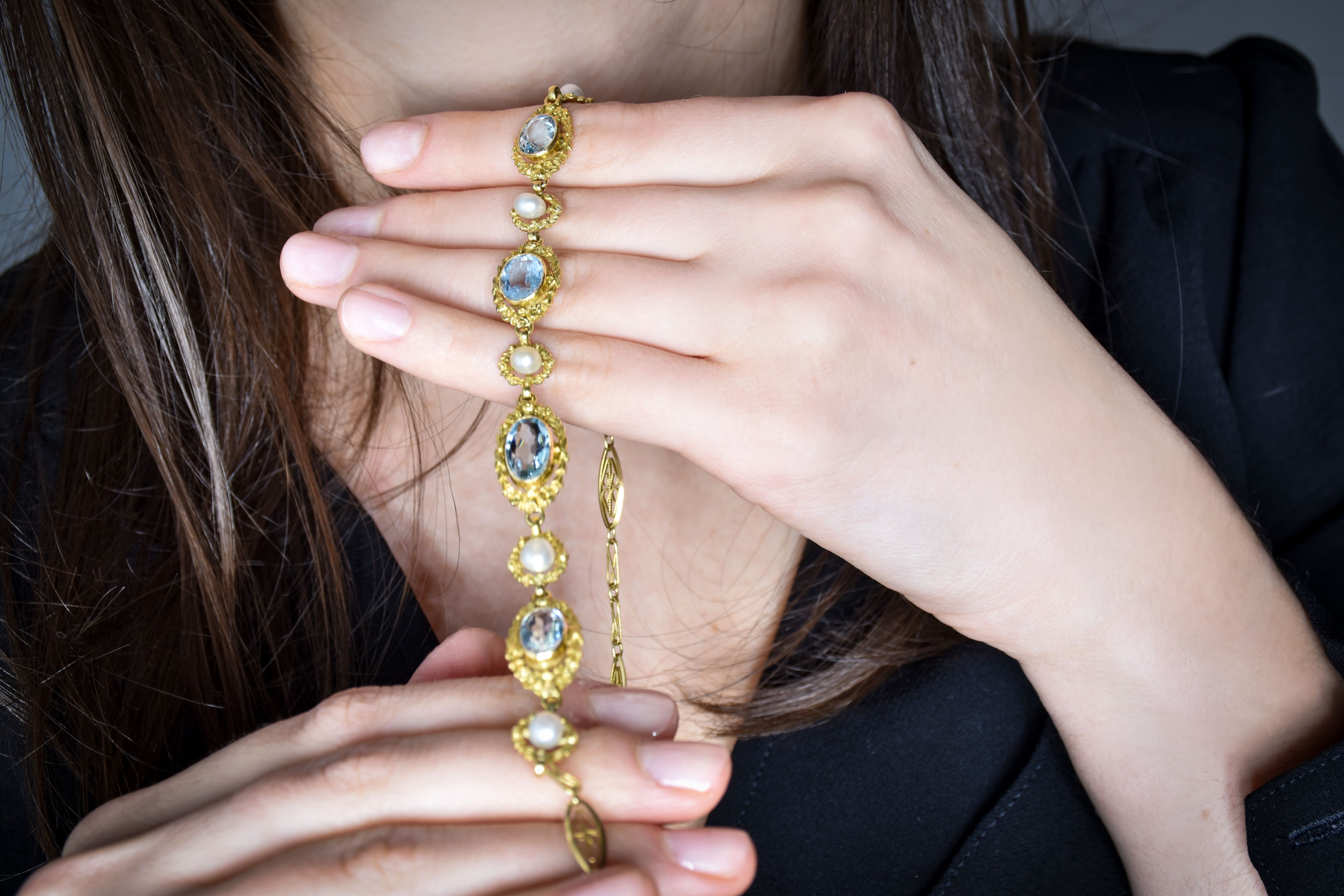 vue dans les mains d'un collier en or orné d'aigues marines et de perles