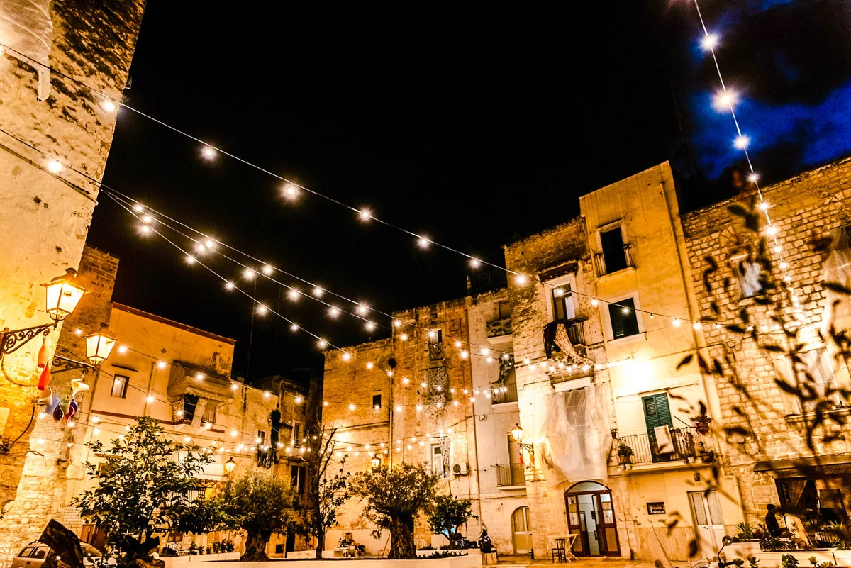 An elegant wedding ceremony setup features a domed gazebo adorned with peach and pink floral arrangements and lush greenery. White chairs line the aisle.