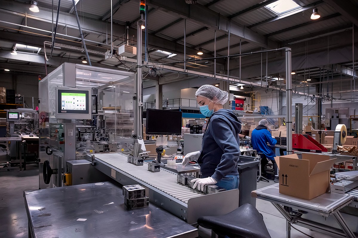 Employée en usine portant un masque et des gants travaillant sur une chaîne de montage, production industrielle – Nord | Photographe pro Anteale | Yann Manac’h