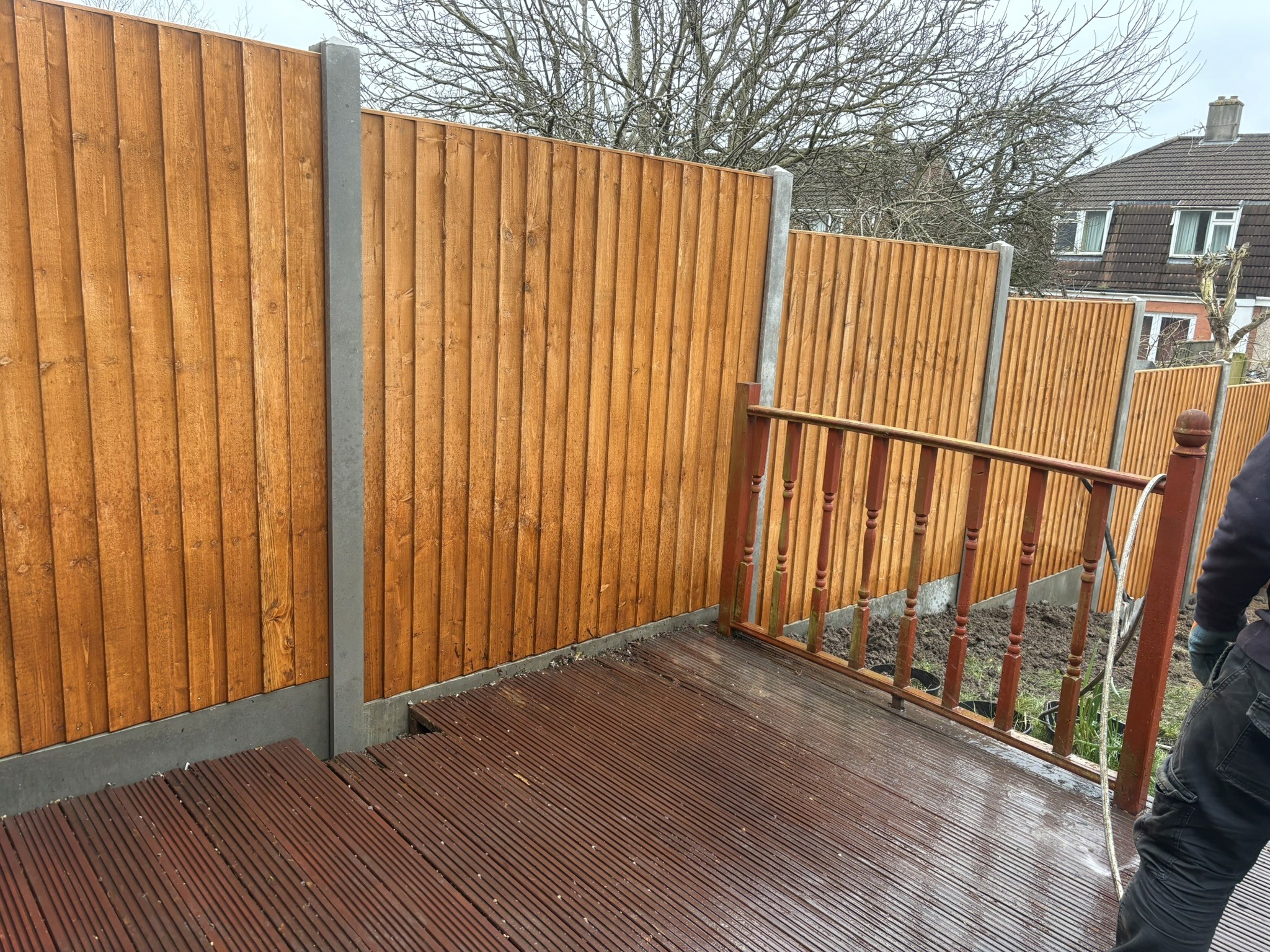 Timber garden fencing with concrete posts beside a decked seating area.