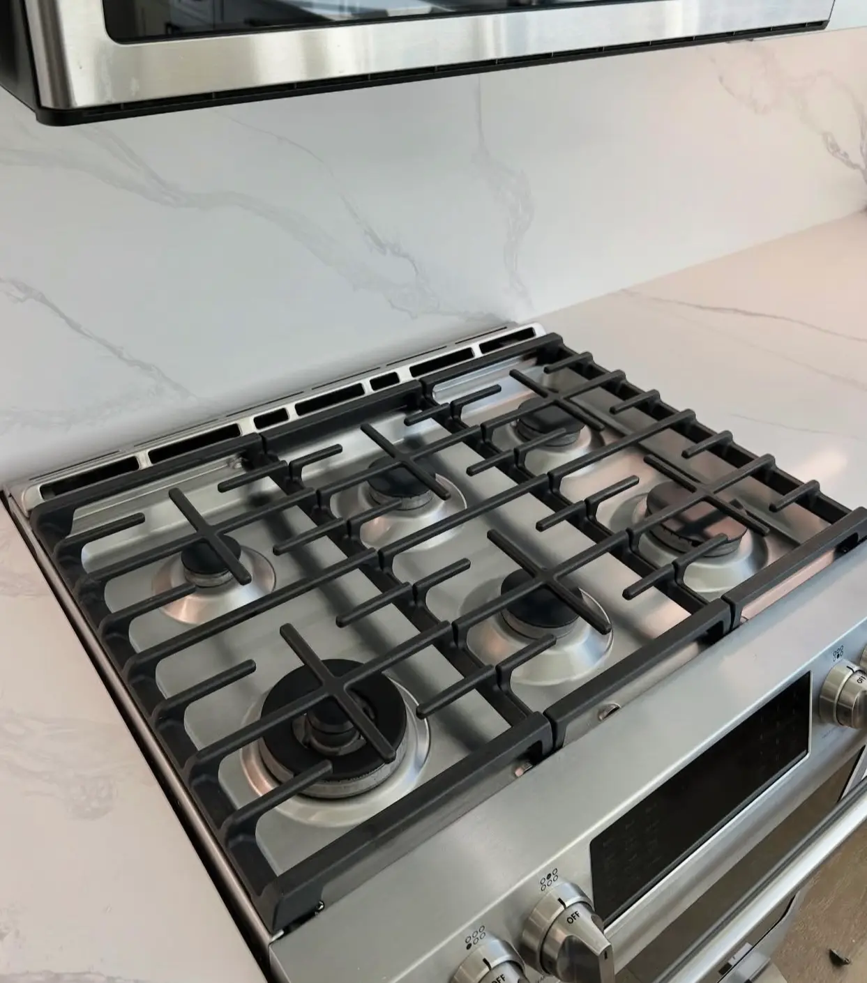 Detailed shot of a professional gas stovetop and marble backsplash, showing a grease-free and polished kitchen surface.