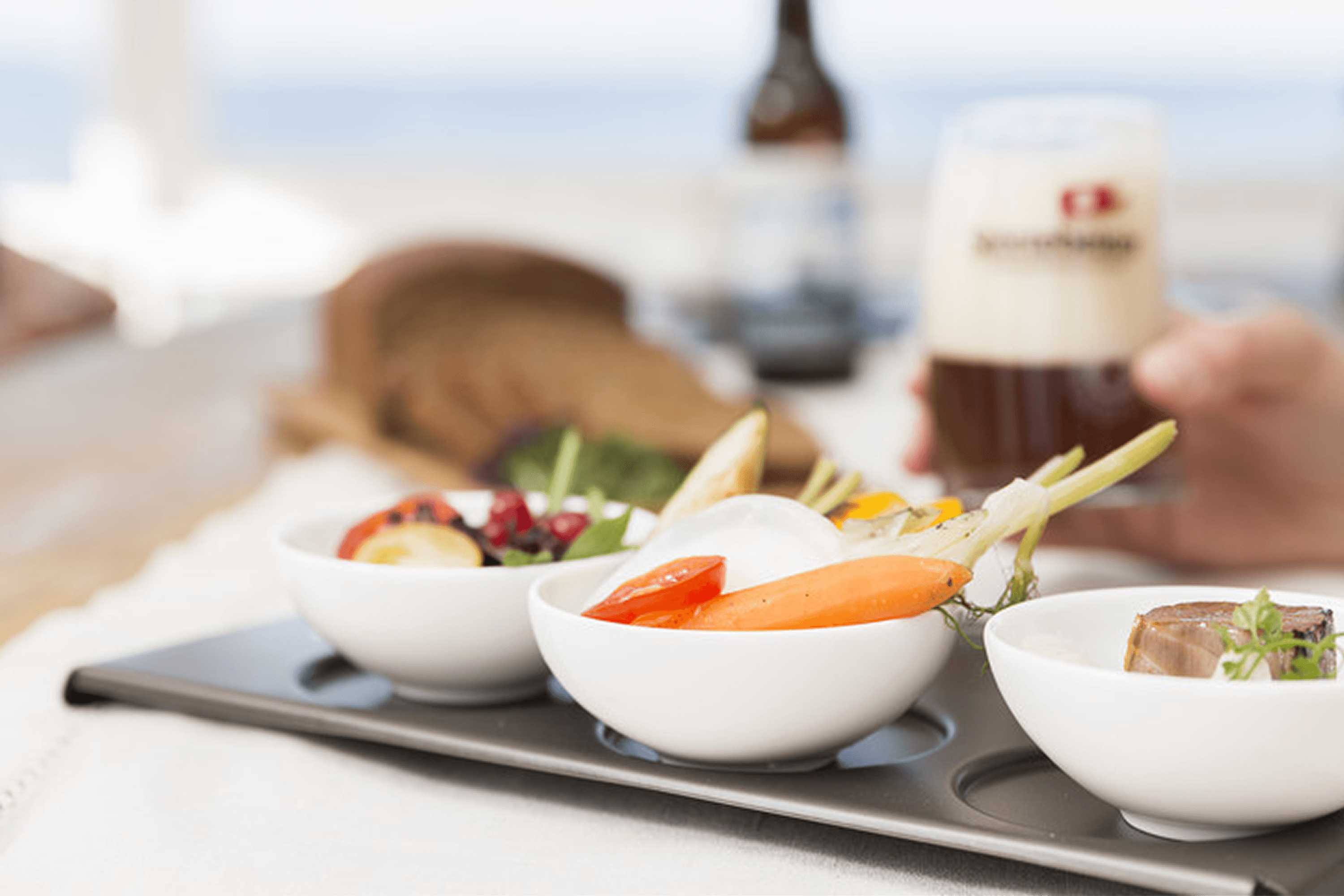 Set of white bowls with food and a beer.