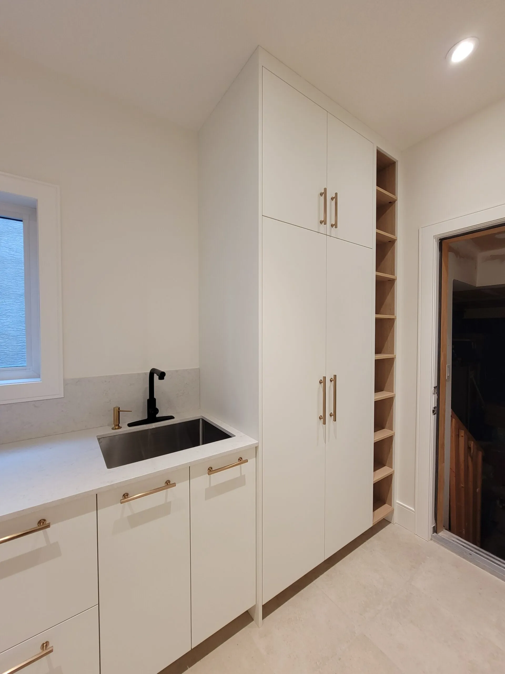 Image of mudroom with shoe storage and small sink.
