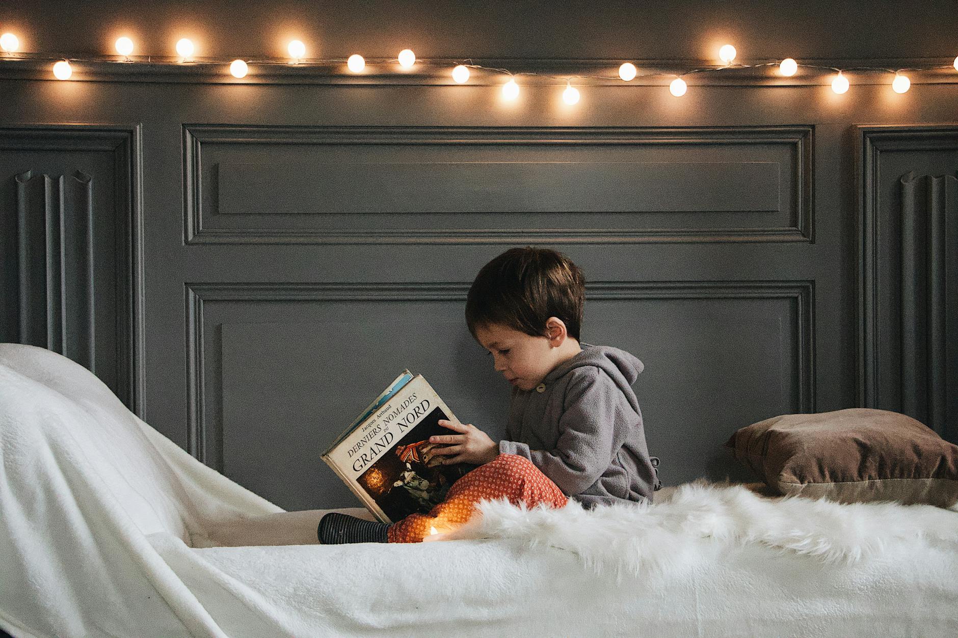 A young girl sitting on a cozy beanbag chair intently reading one of her first chapter books for 7 year olds.