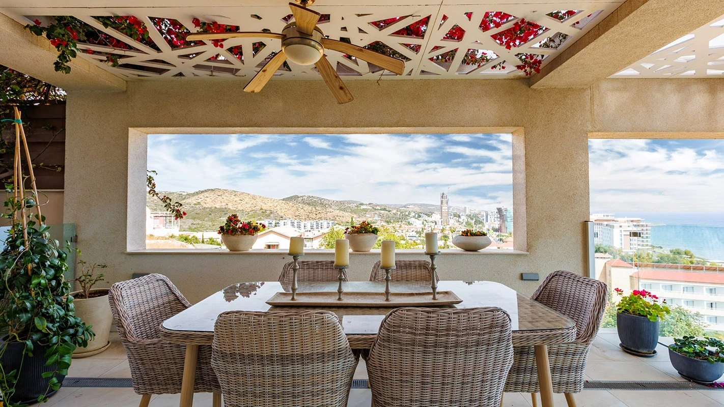 Seafront Residence Limassol covered terrace dining area with woven chairs, patterned ceiling panels, and wide coastal views
