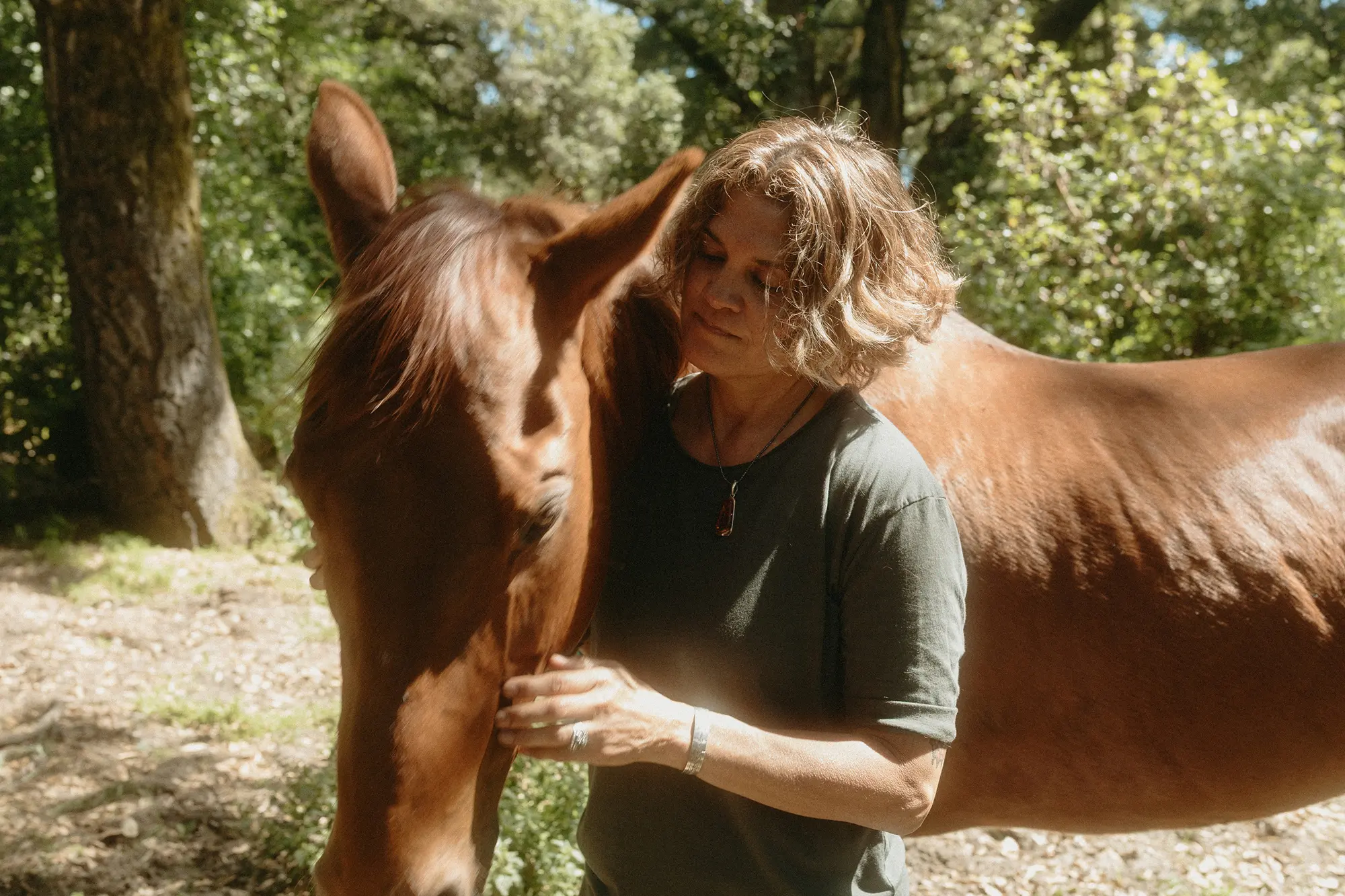 Sonia tenderly embracing Corona the horse in a sunlit garden