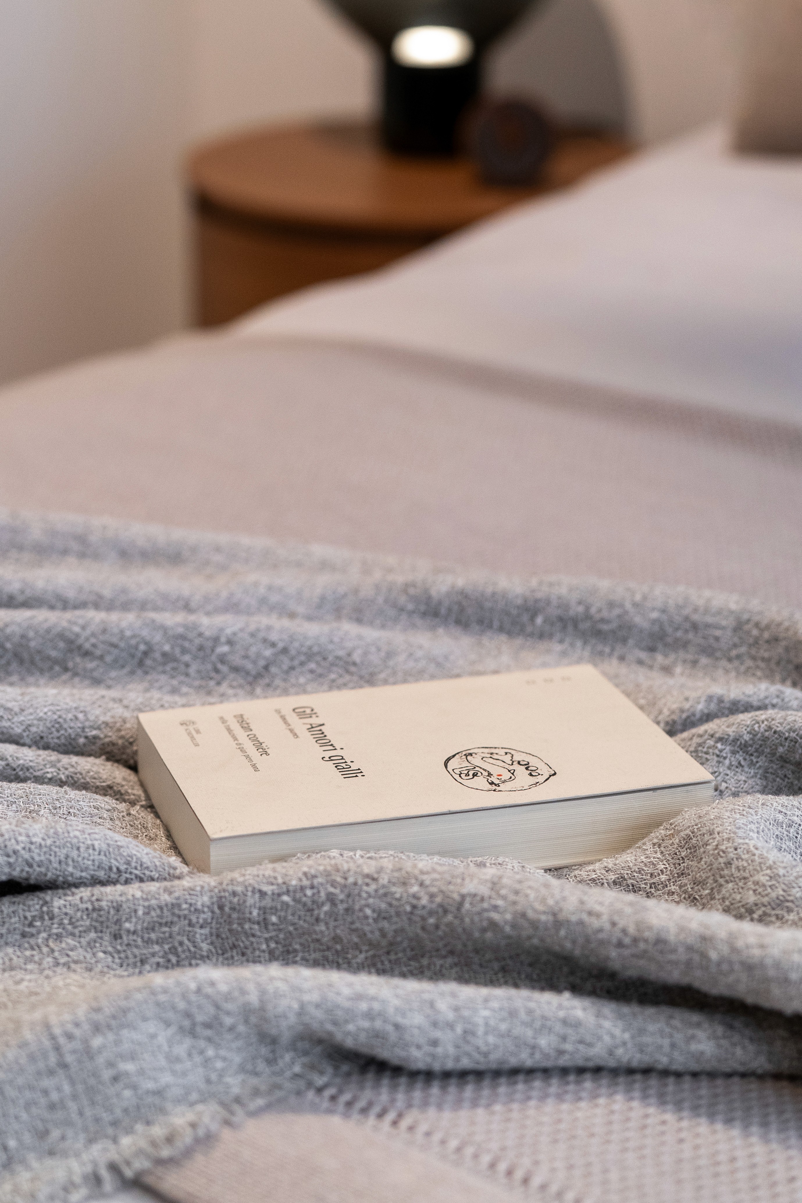 Libro sobre cama con manta y nórdico de color gris