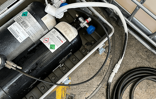 Four diverse professionals collaboratively working on a laptop, with one person pointing at the screen while others observe.