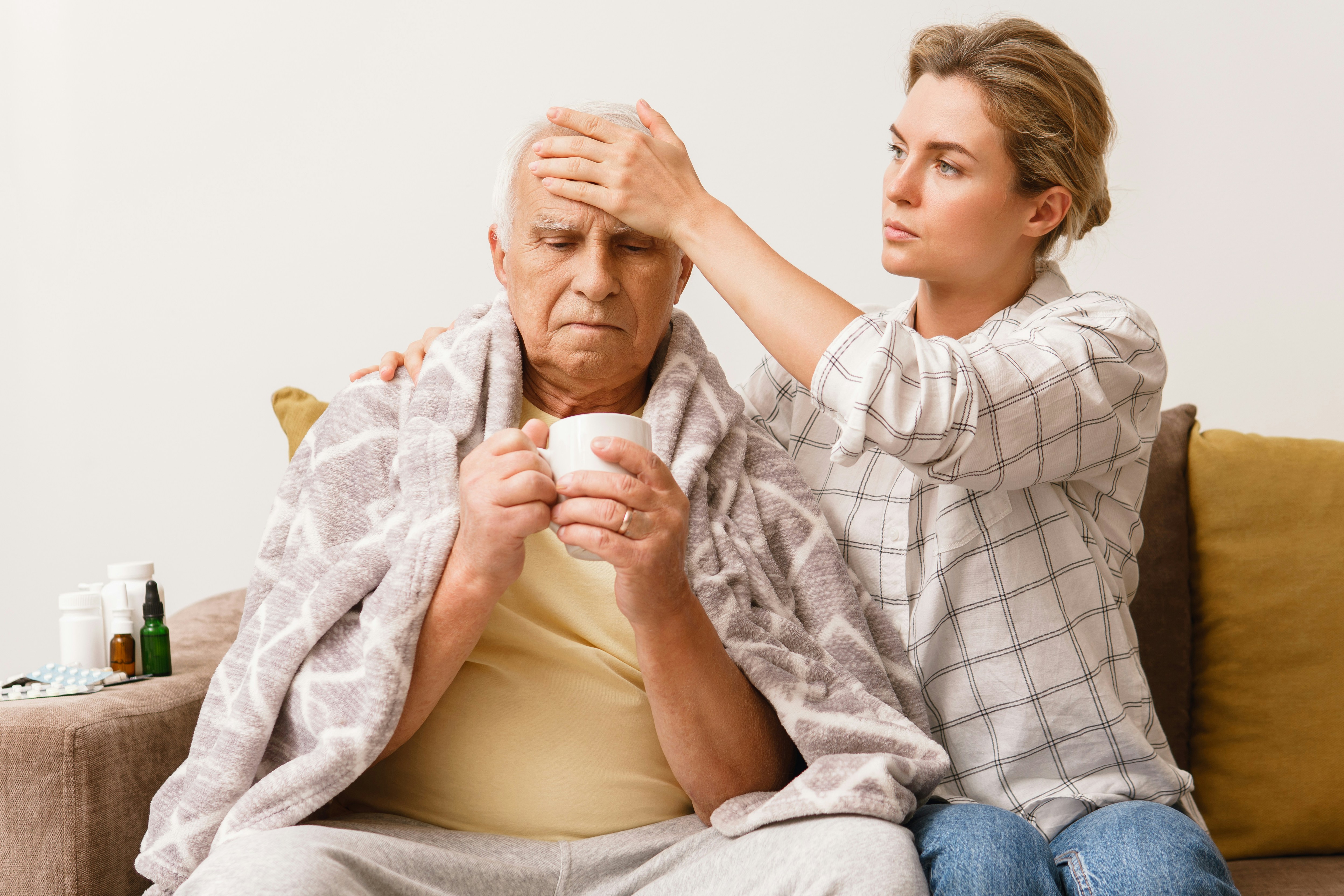 young woman checking older man for signs of fever