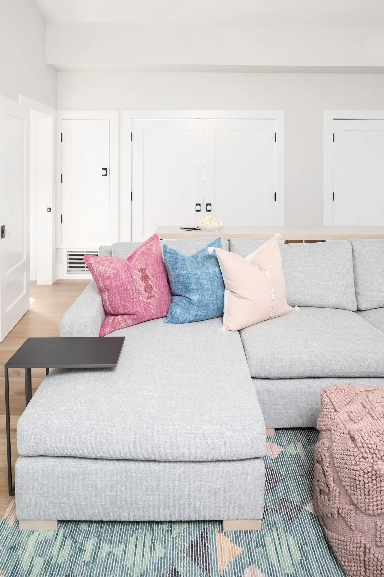 Cozy sectional with colorful cushions in North Tustin Remodel & Addition's serene living space. Photo by Molly Rose.
