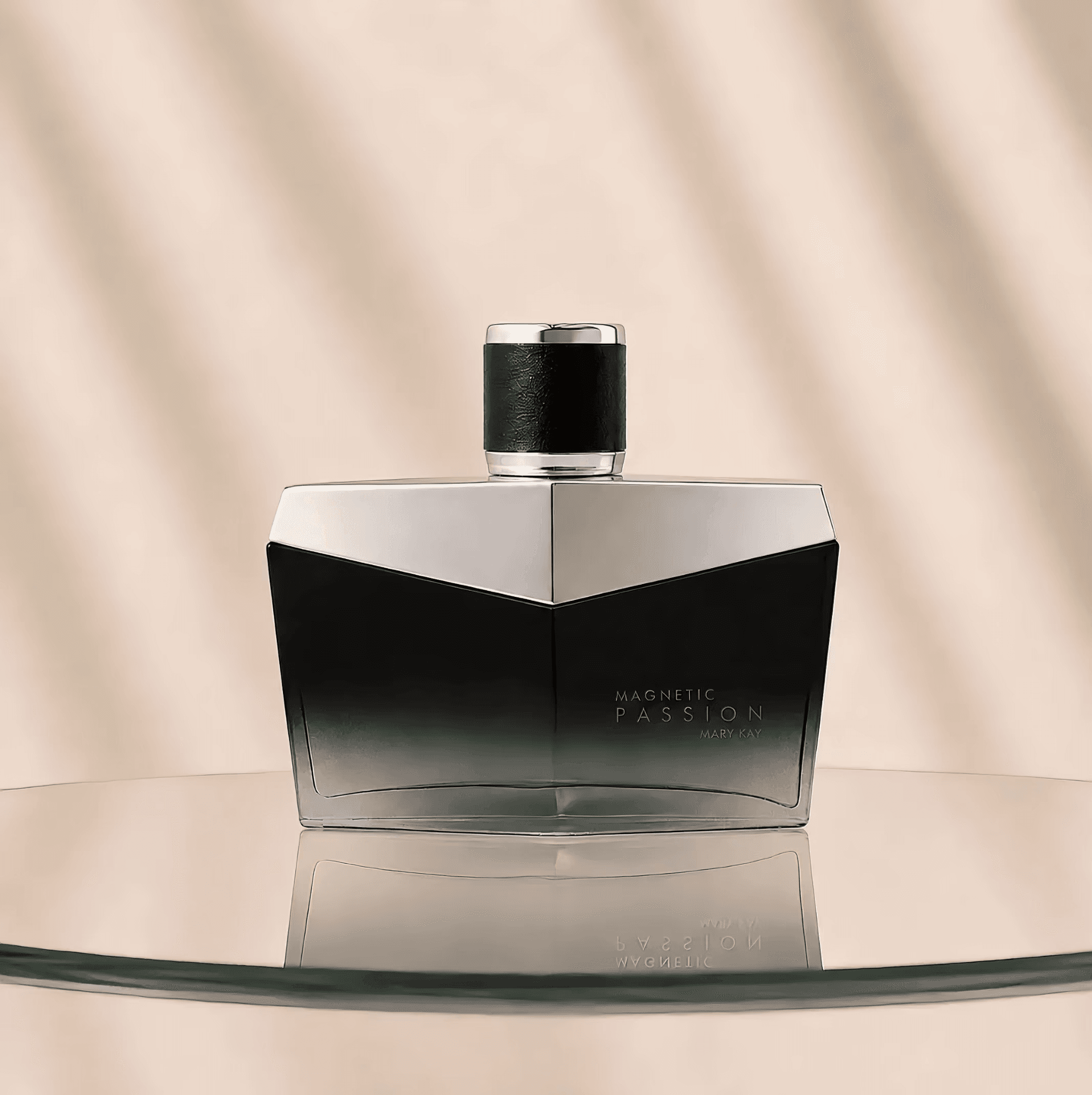 Frasco preto e prateado da Magnetic Passion™ Deo Parfum Mary Kay sobre base de vidro e fundo bege.
