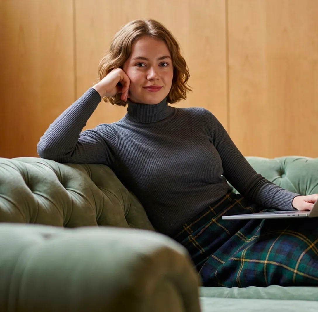 A woman sitting on a velvet sofa holding a tablet