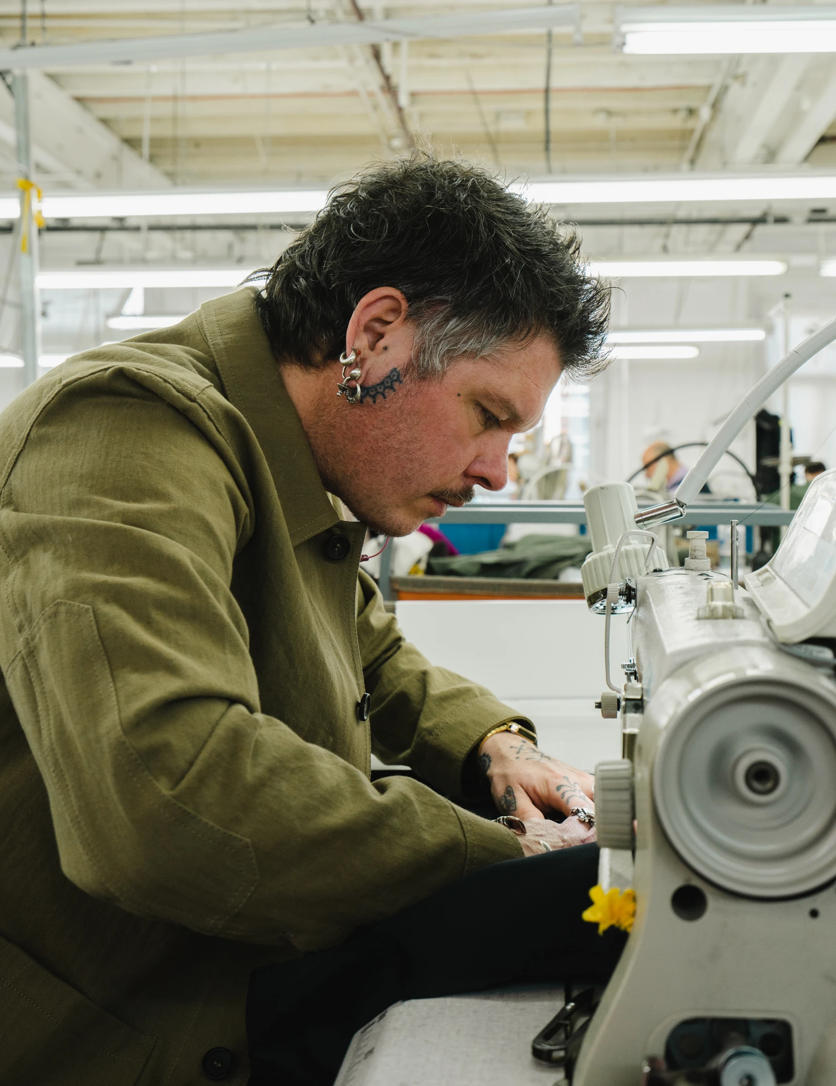 A smiling woman with her arms crossed, standing against a dark green background. She has long, dark hair.
