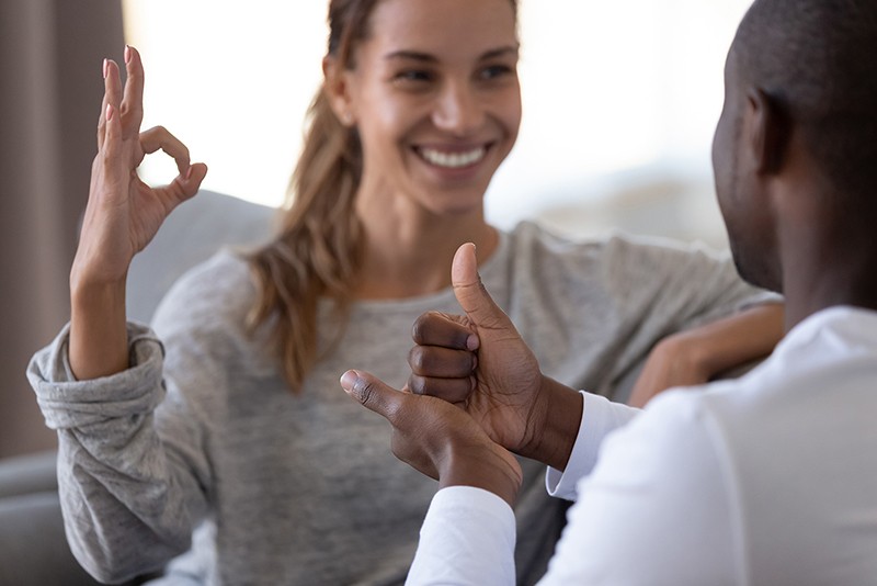 Femal colleague displaying the okay sign with her hand and a male showing thumbs up