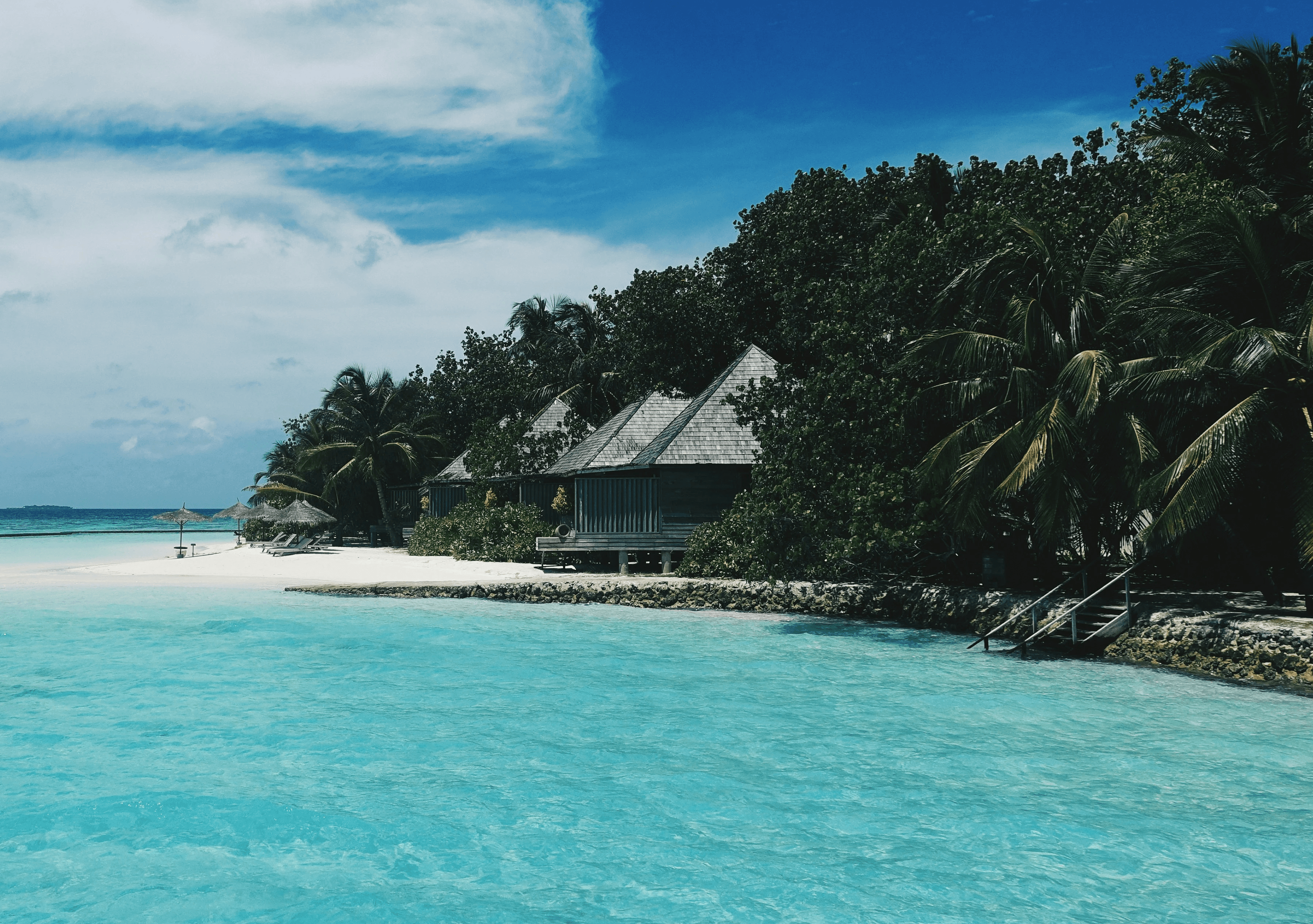 Photo of Maldivian coast with beachfront villas in the background.