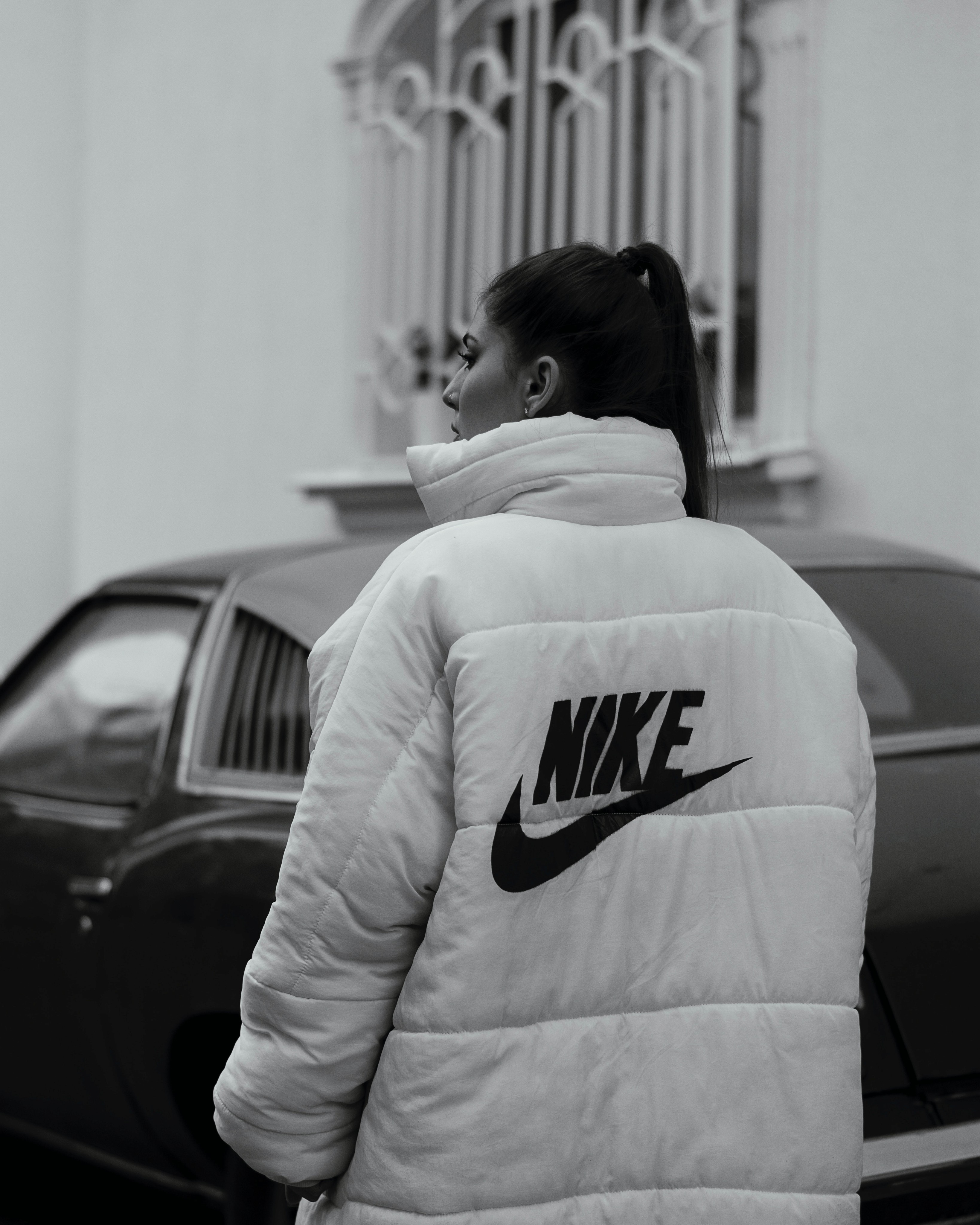 Woman in white and black Nike hoodie standing near a car