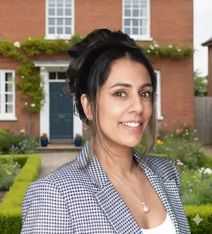 Woman with dark hair pulled back, wearing a black and white checkered blazer, smiling at camera