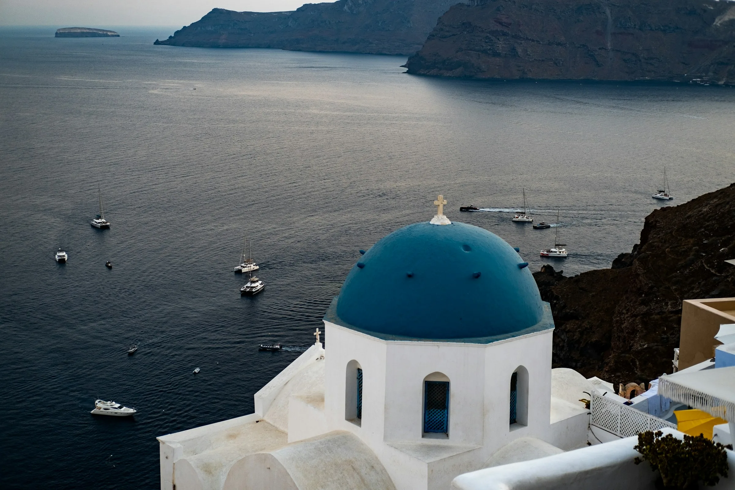 A white chapel with a blue dome above the sea