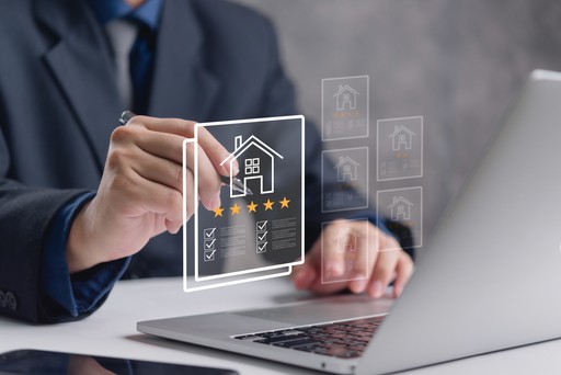 Person am Laptop mit holografischer Hausdarstellung, fünf Sternen und Checkliste – Symbol für Immobilienbewertung bei Wohnvision