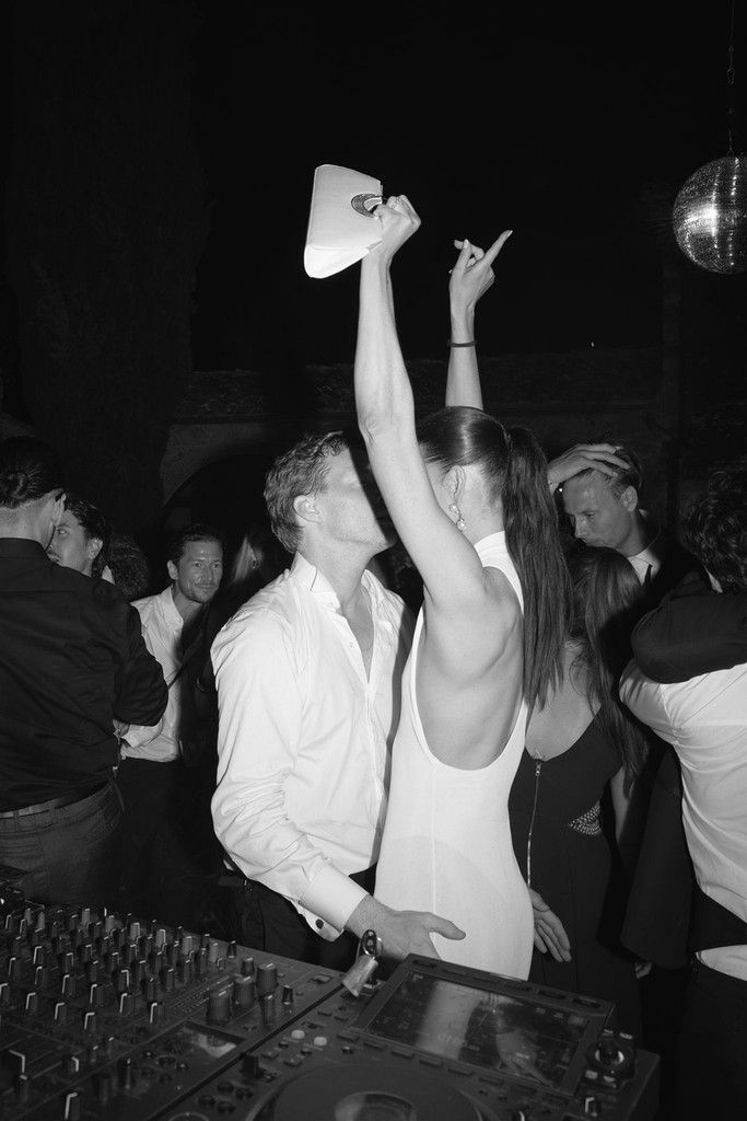 Black-and-white flash image of bride throwing her hands in the air on the dancefloor