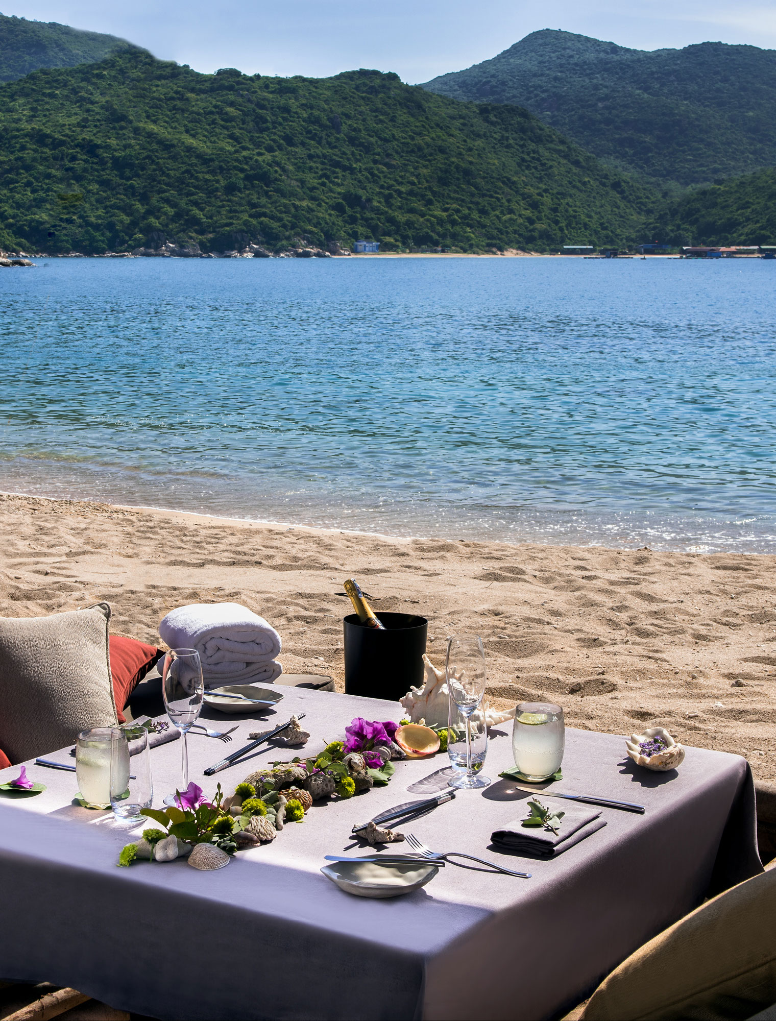 Beachfront dining setup at Amanoi with turquoise waters and forested hills
