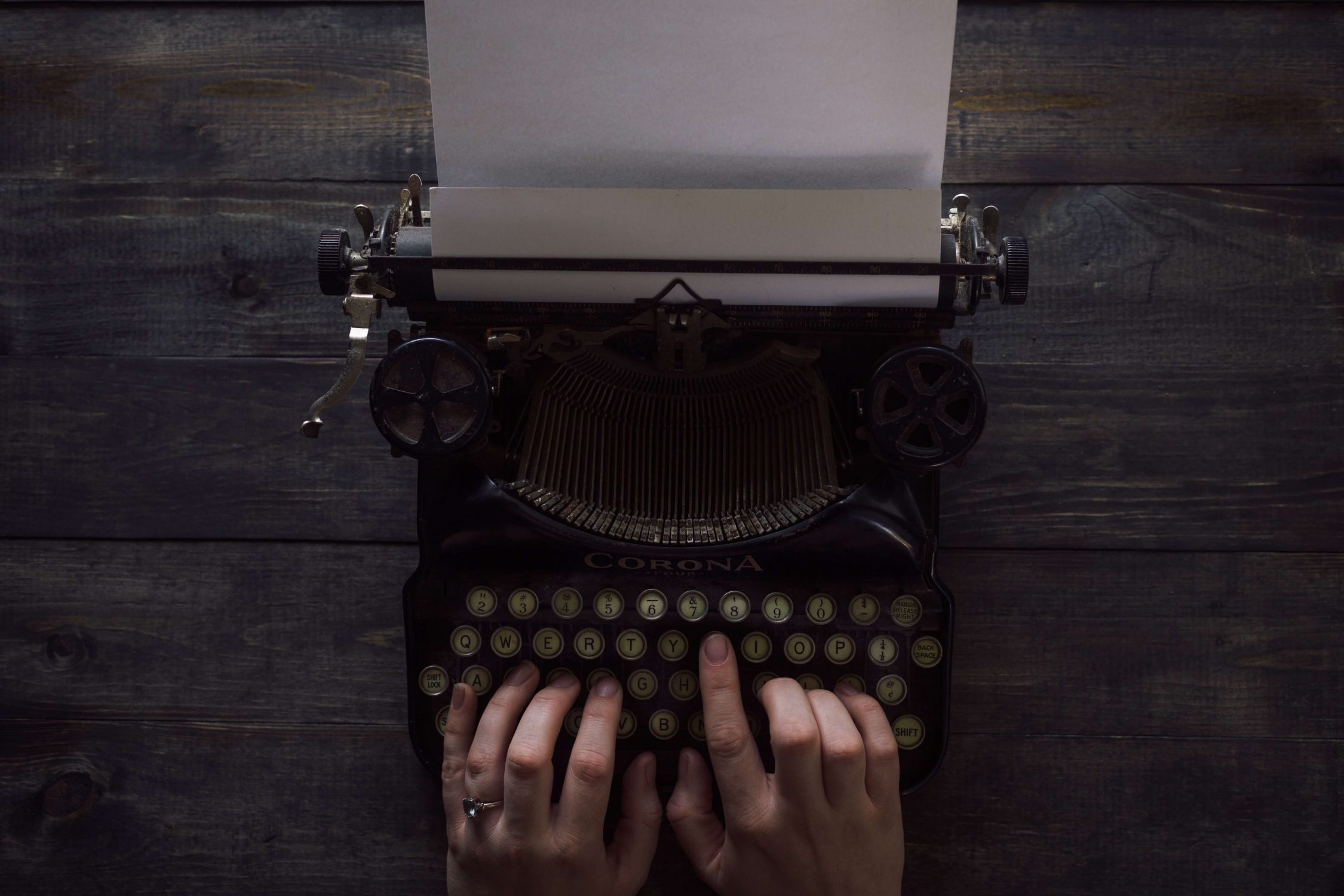 A person typing on a typewriter, symbolising the blogs being written for the best investing blogs.