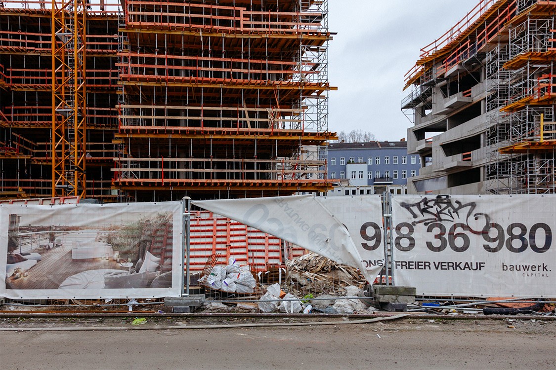 Construction site with partially built buildings and a large advertisement banner in the foreground.