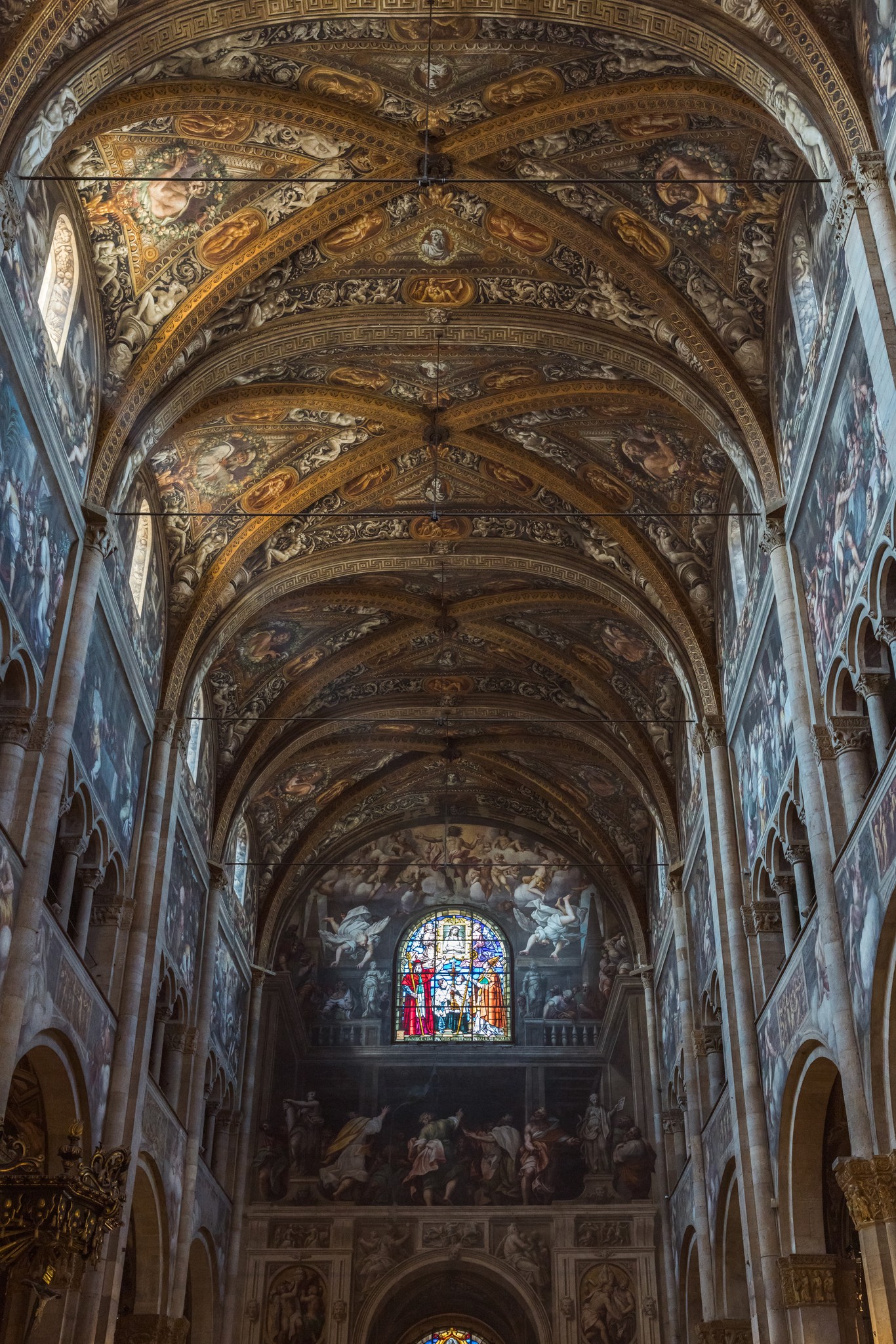 Navata della chiesa con volta a botte affrescata, altare illuminato da vetrata colorata, cerimonia matrimoniale in corso