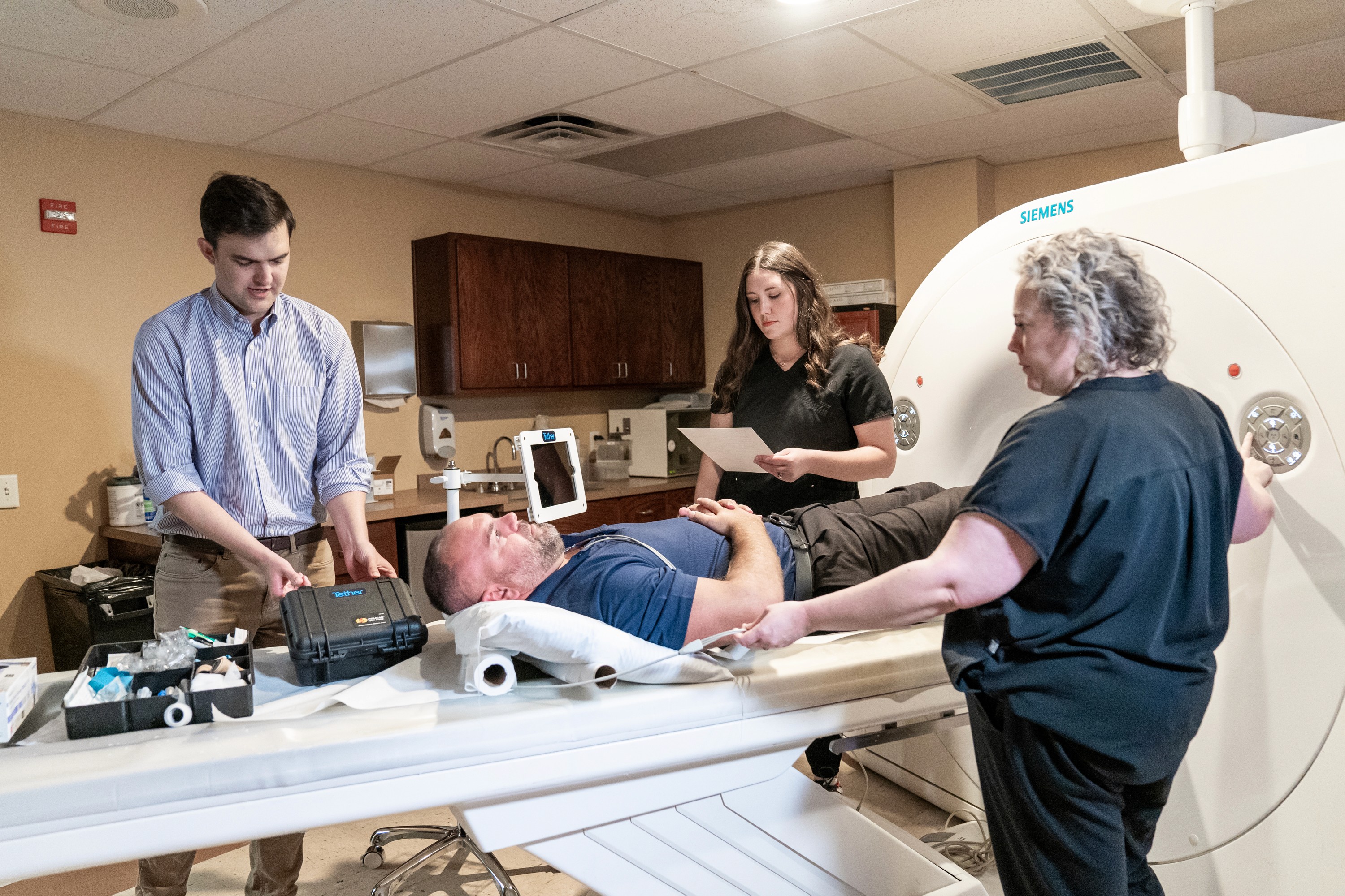 Radiology technologists preparing a patient for a CT scan inside an outpatient imaging center, demonstrating Tether Supervision’s standardized contrast workflows, real-time virtual direct supervision model, and safety-focused clinical practices.
