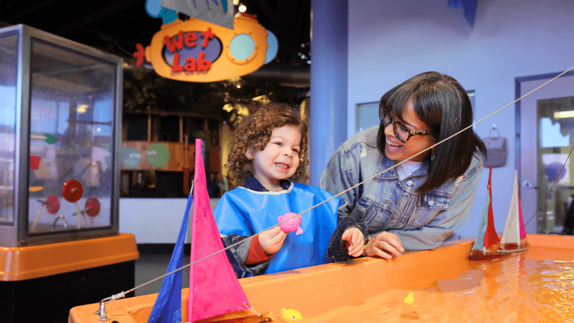 A young boy and mom make a toy boat to put in the water at the Wet Lab.