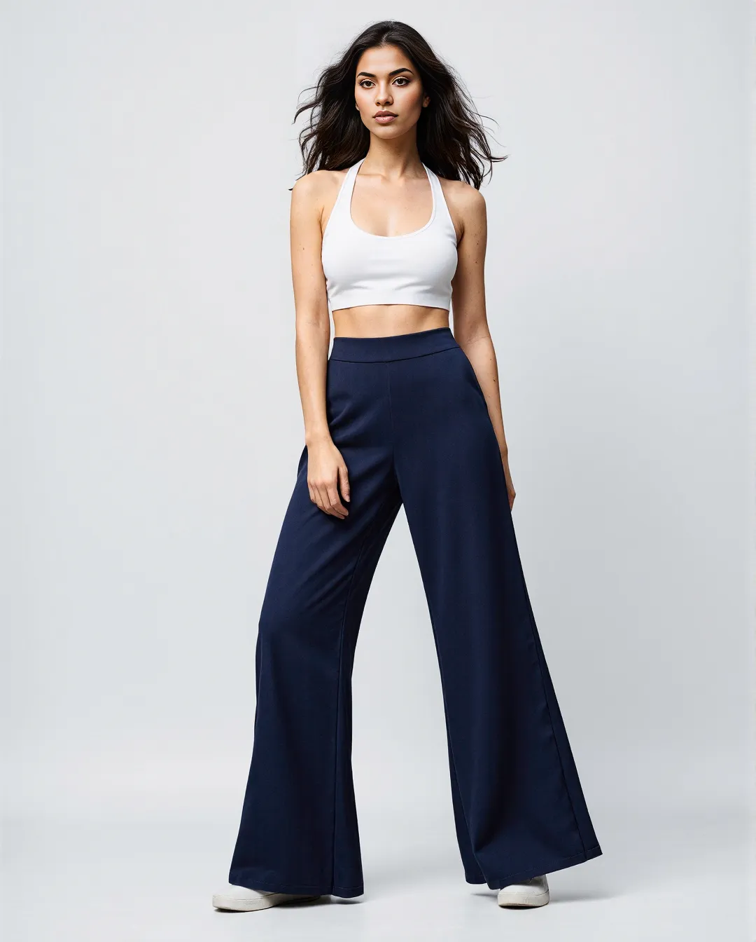 Fashion photography featuring a white crop top paired with flowing navy wide-leg pants against a minimal light background.