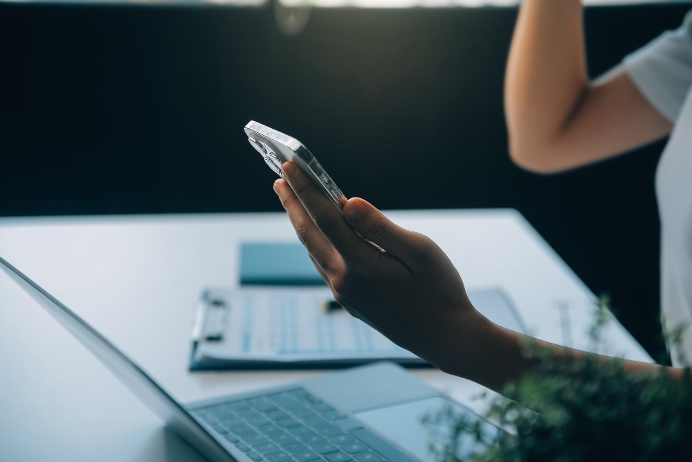 Person using a smartphone in a dimly lit office, representing flexibility and pay-as-you-need pricing.