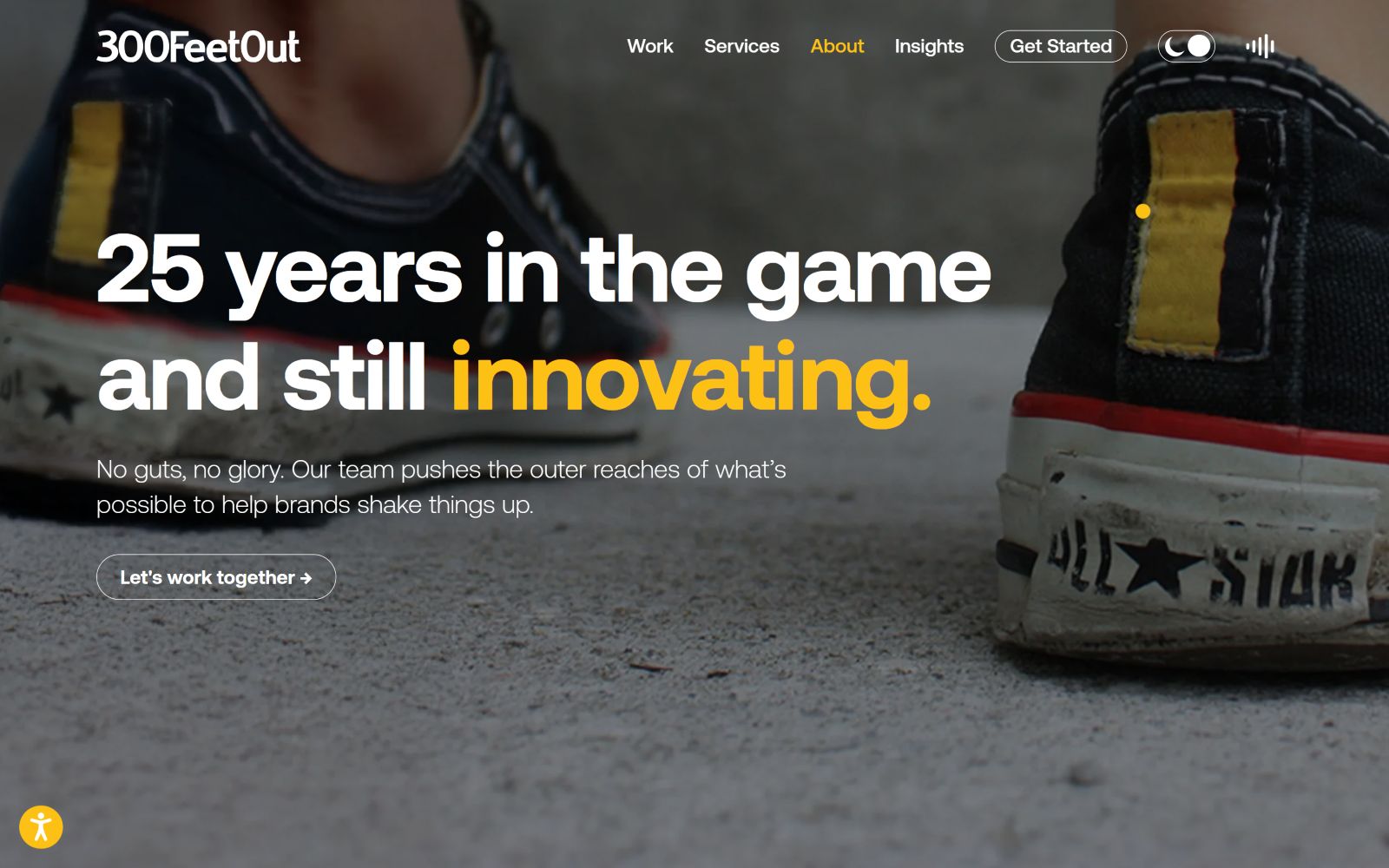 Close-up of sneakers on sandy ground. Text: "25 years in the game and still innovating." Buttons: "Let's work together.