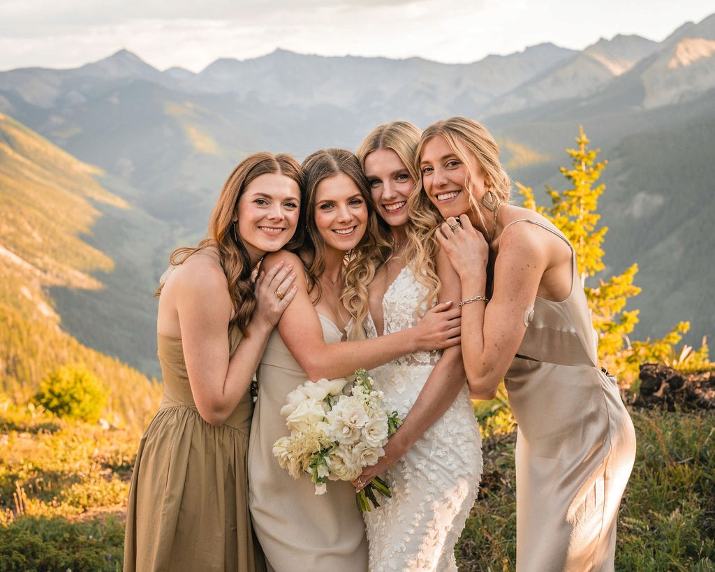 Bride embracing three attendants with mountains behind them