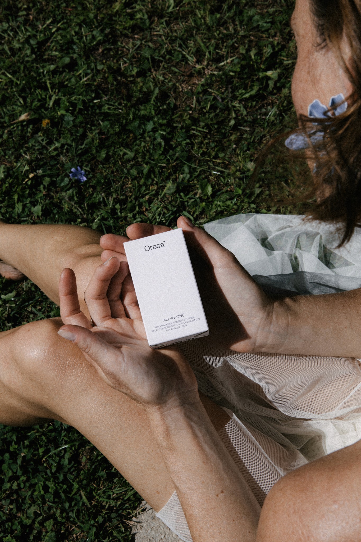 Frau hält Oresa Produktbox im Wiese
