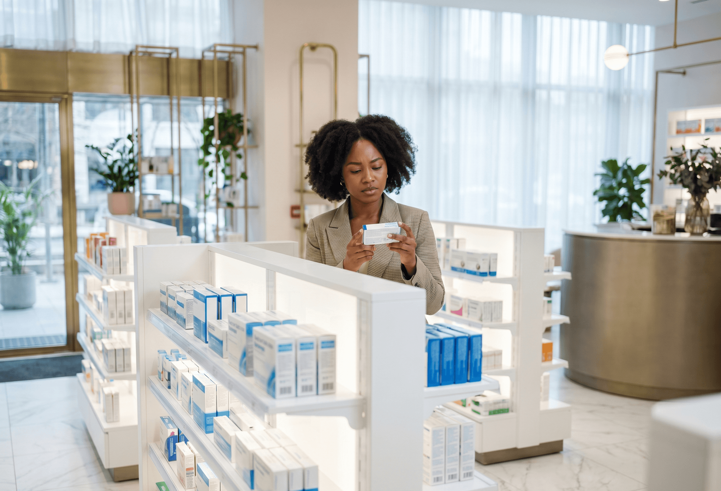 A young black woman carefully reading the label of an over-the-counter (OTC) medication at a luxury boutique pharmacy