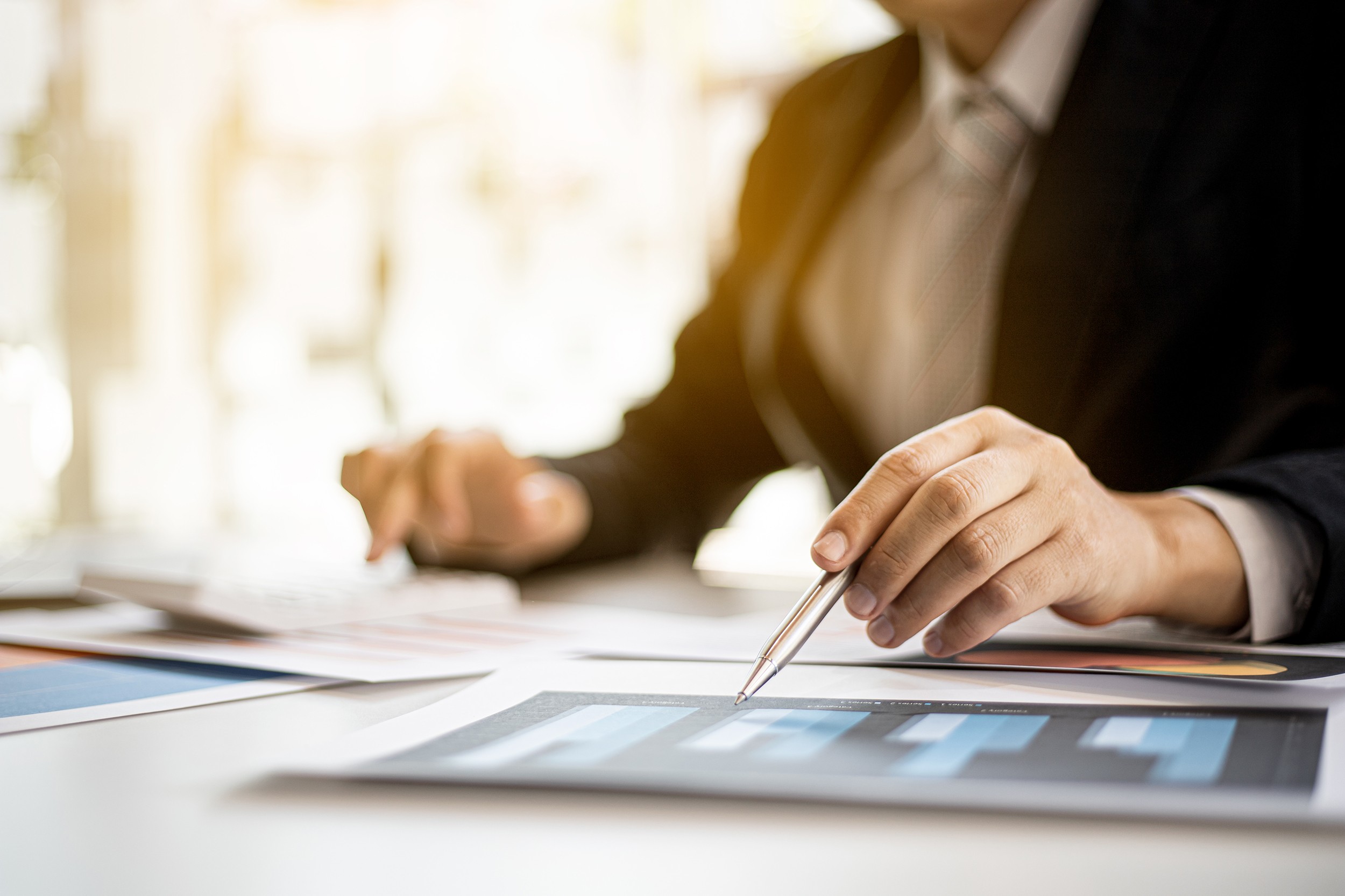 Businessmen are examining company financial information from documents prepared by the finance department, financial documents placed on their desks displayed in bar charts. Financial concept.
