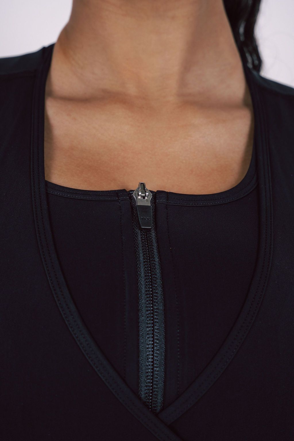 Detail-shot-of-a-black-zip-up-sports-bra-neckline-highlighting-the- quality-full-length-zipper-and-V-neck-stitching
